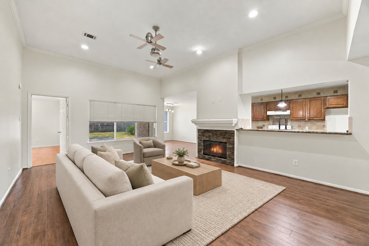 A stone-faced fireplace anchors the living room, and the broad kitchen opening makes conversation easy. Virtually staged.