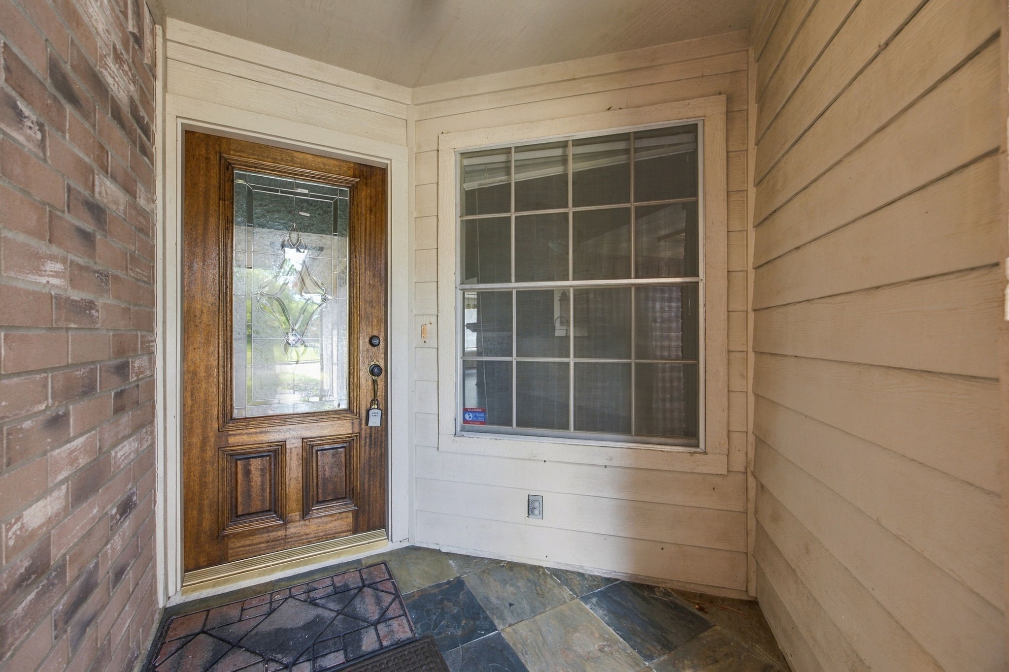 A sheltered front entry features tile flooring and a wood door with decorative glass.