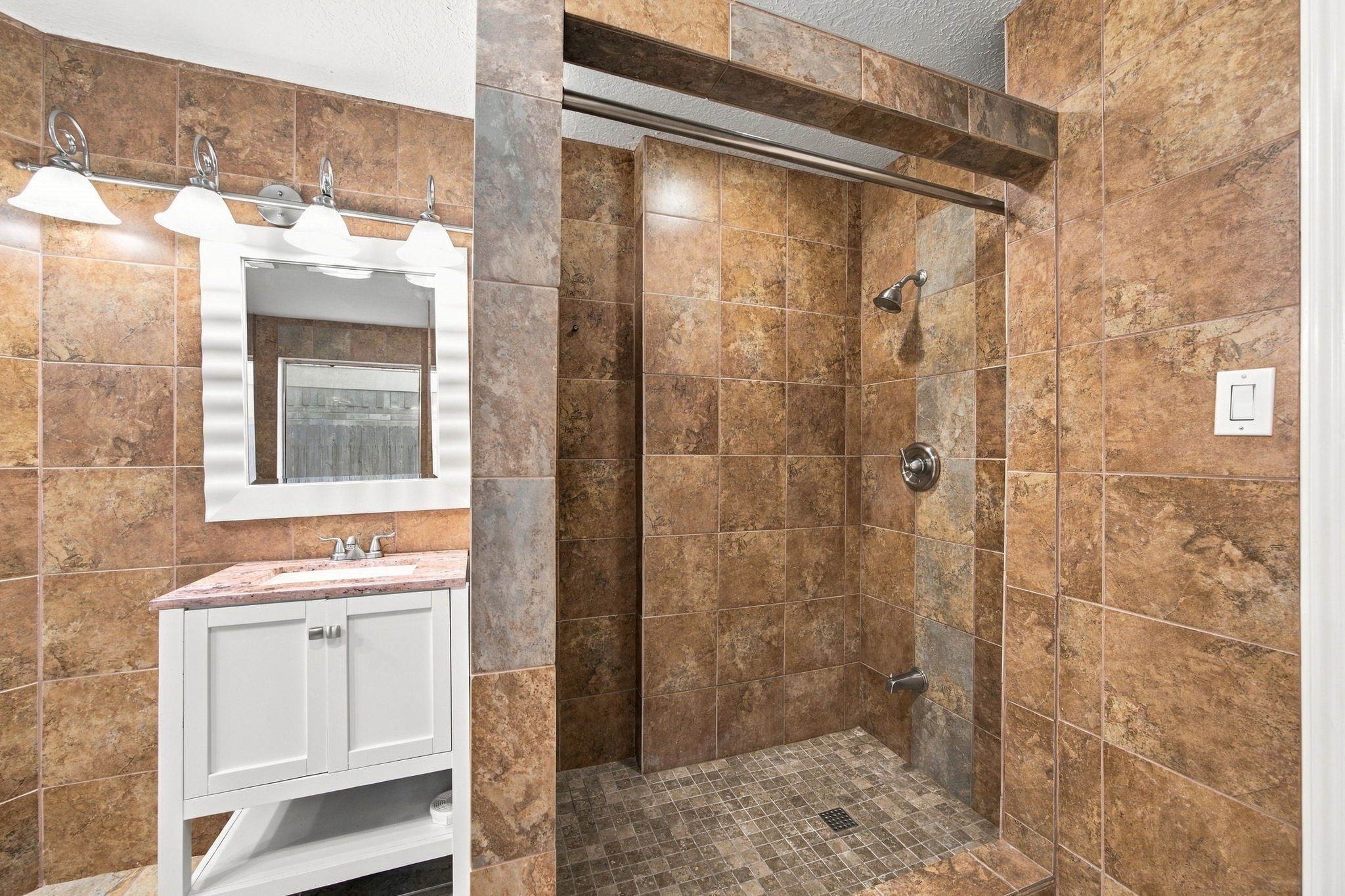The walk-in shower features floor-to-ceiling tile and a mosaic tile floor.