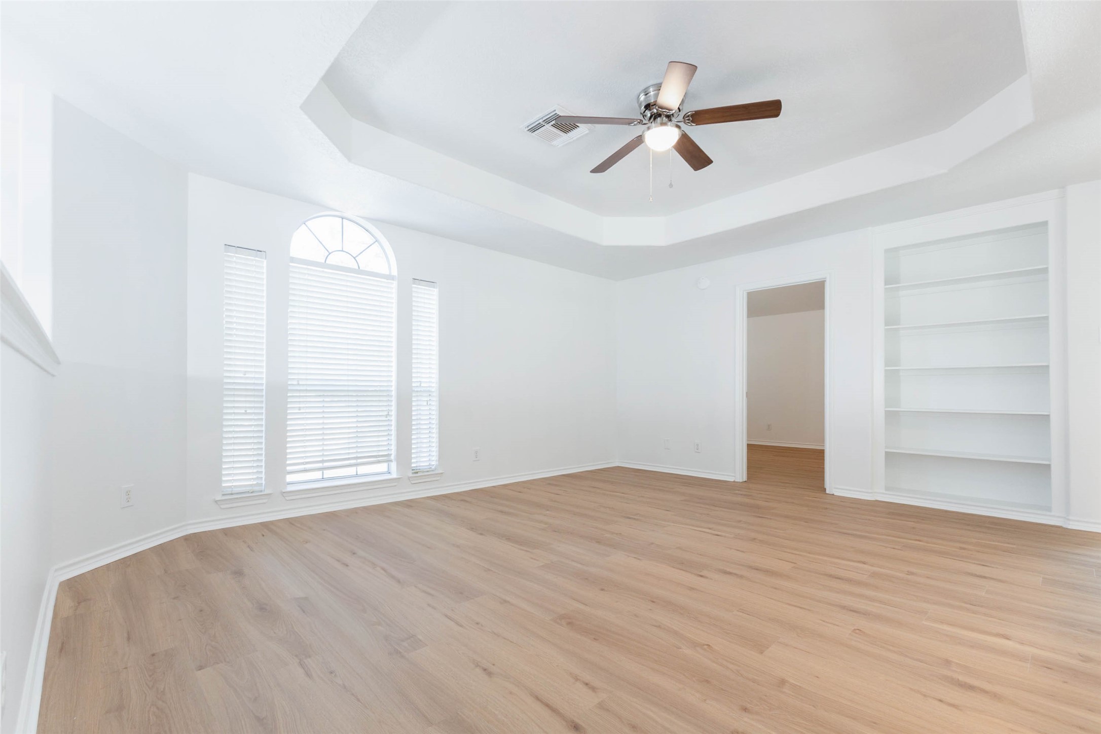 The expansive upstairs game room offers a fabulous secondary living space, featuring gorgeous luxury vinyl plank flooring, an elegant tray ceiling, & a ceiling fan. Generous windows welcome abundant natural light, while built-in shelving adds character & functionality.