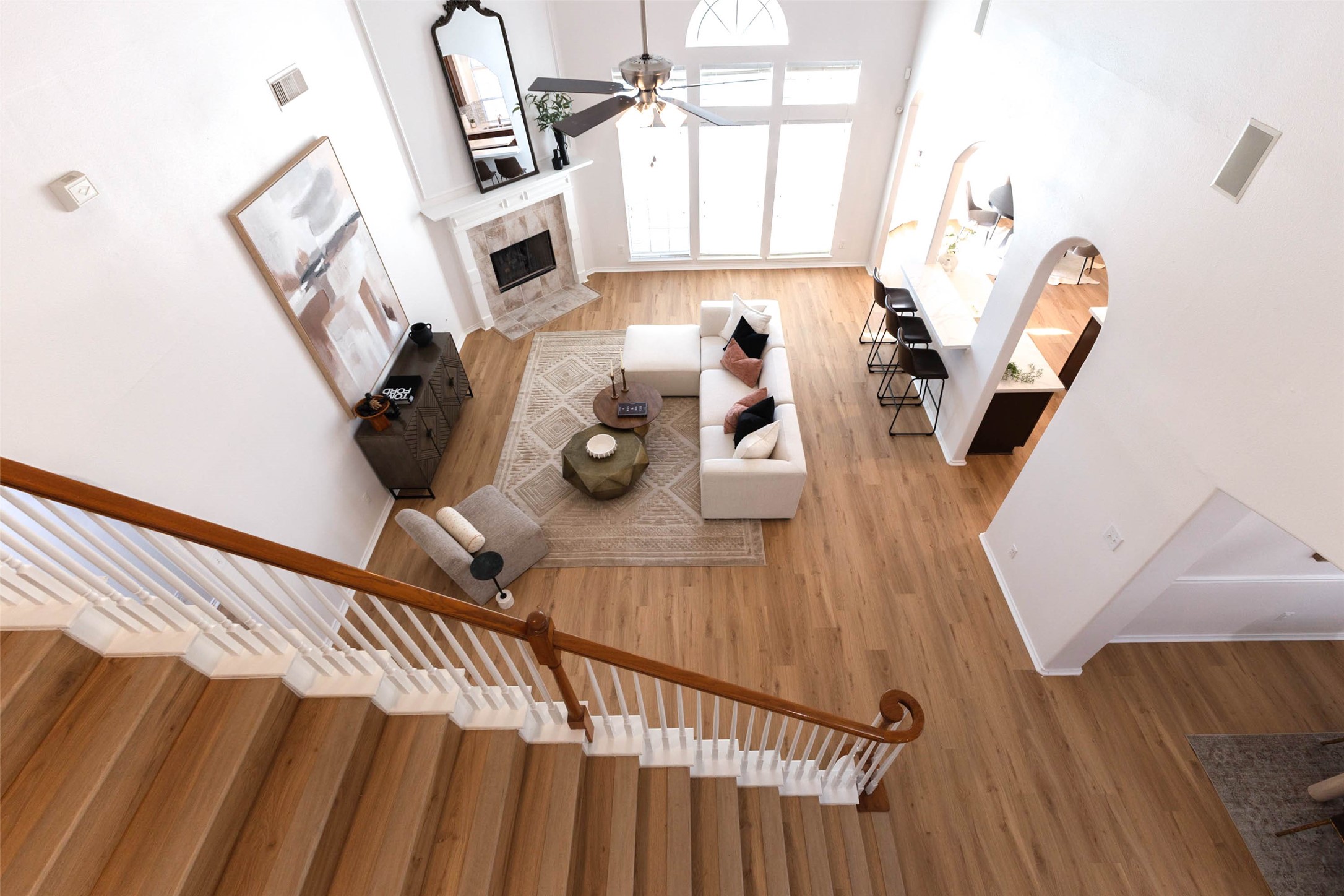 This striking view from the second-floor game room captures the impressive scale of the family room. Soaring ceilings, expansive windows, & gorgeous luxury vinyl plank flooring enhance the grand design, while the open overlook creates a seamless visual connection between the home's upper & lower living areas.