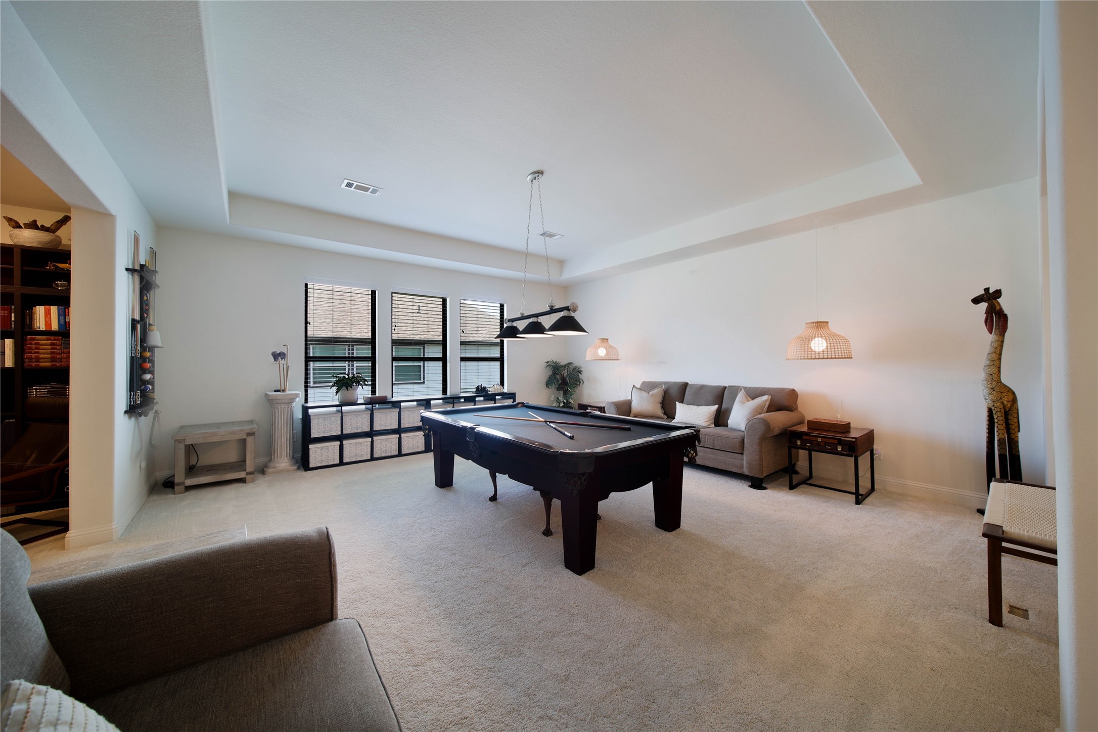 The spacious game room features a stylish tray ceiling, adding architectural interest and an elevated touch to this versatile space.