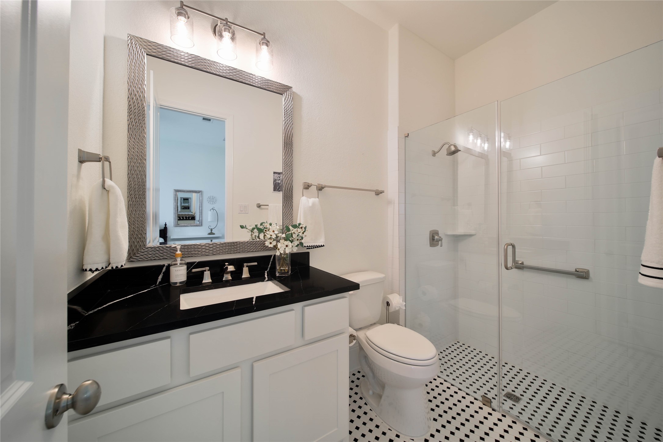 The ensuite bath features a mud-set walk-in shower, striking finishes, and a beautifully designed space that feels both stylish and sophisticated.