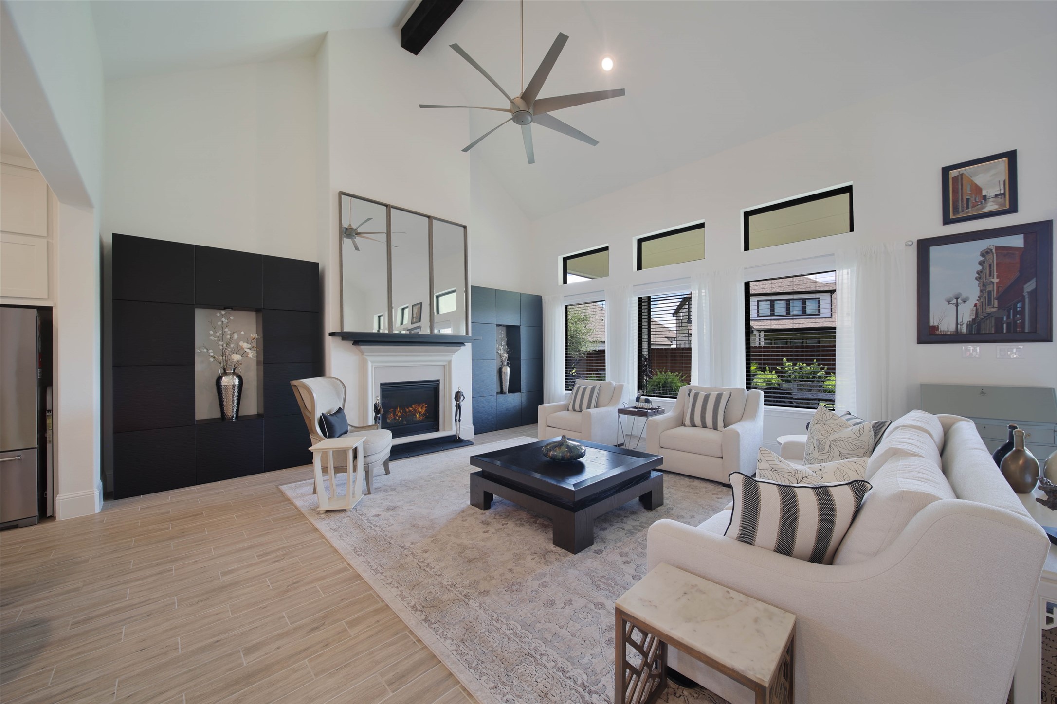 The cast stone gas-log fireplace and striking wood beam on vaulted ceiling  create stunning focal points in the living room, adding warmth, character, and architectural appeal.