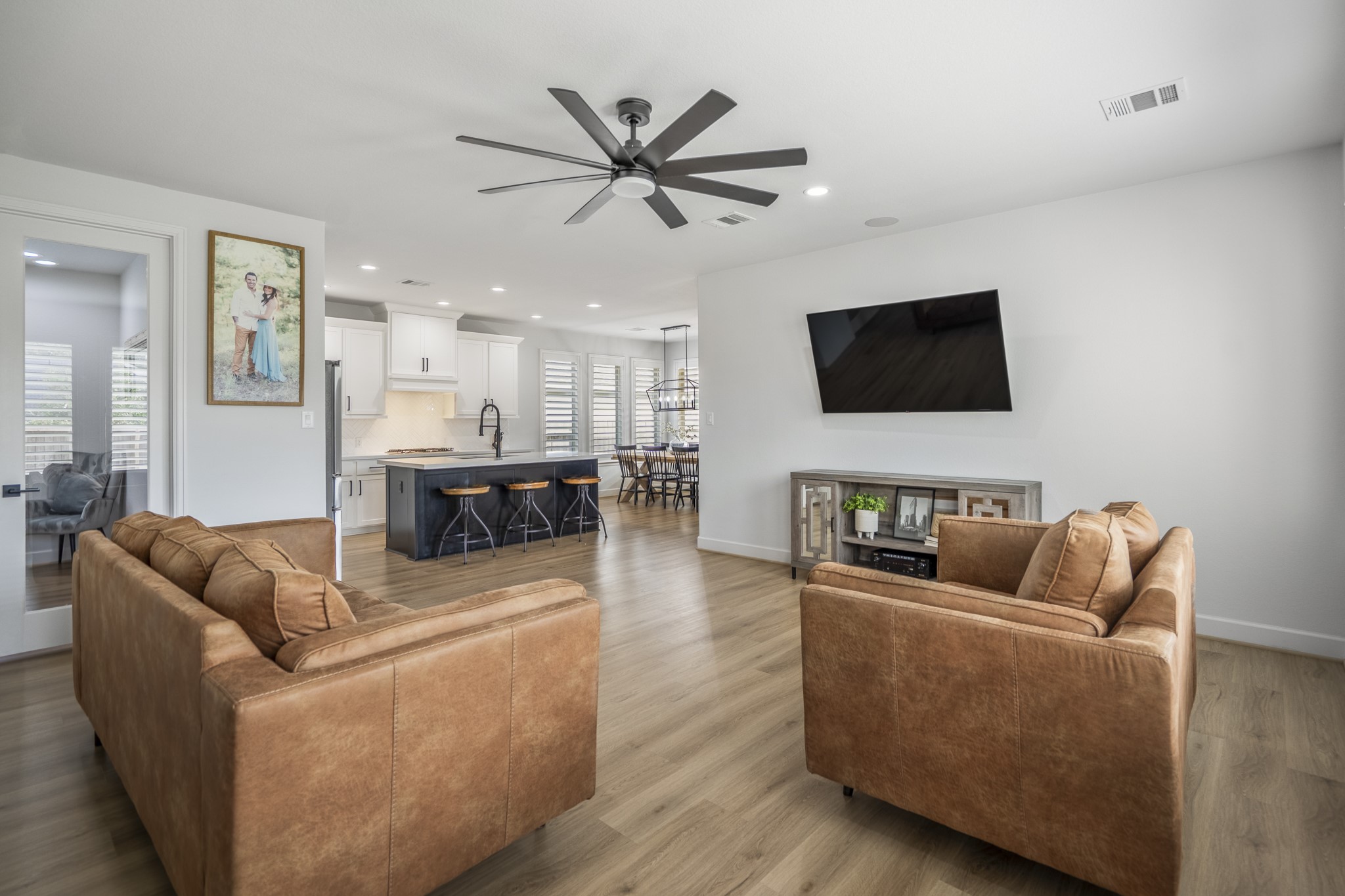 This modern living space features an open floor plan with a spacious kitchen, sleek island, and dining area. The room is bright with natural light and has stylish finishes at every turn.