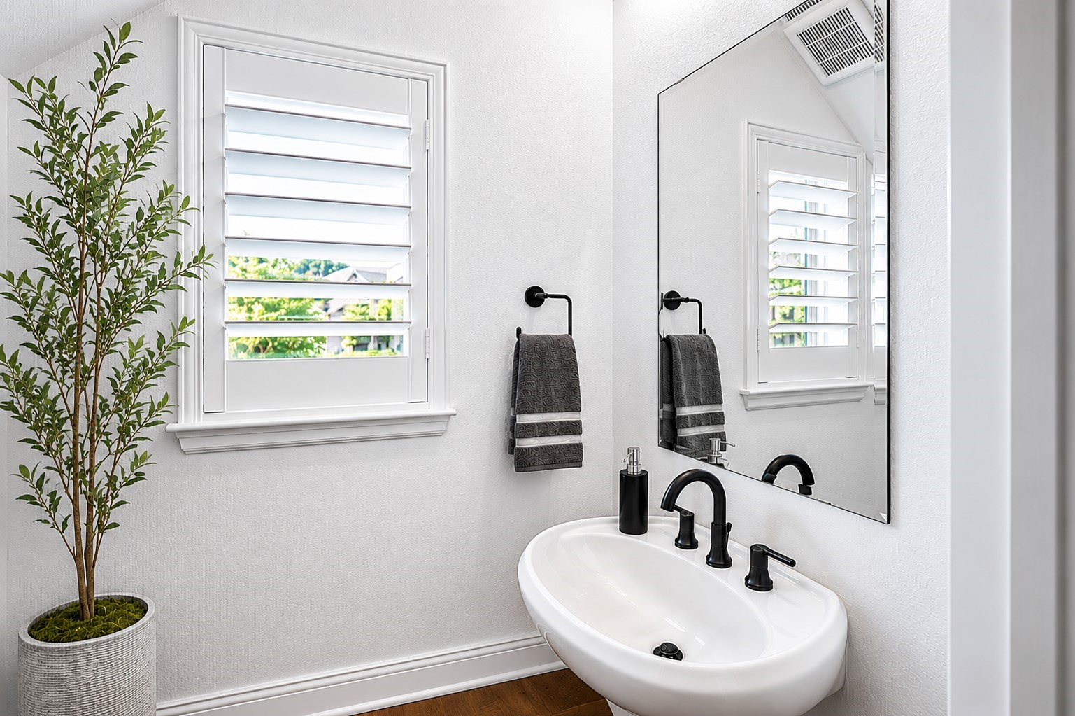 Natural light filters through the plantation shutters and black fixtures add a touch of style to this first-floor half bath.