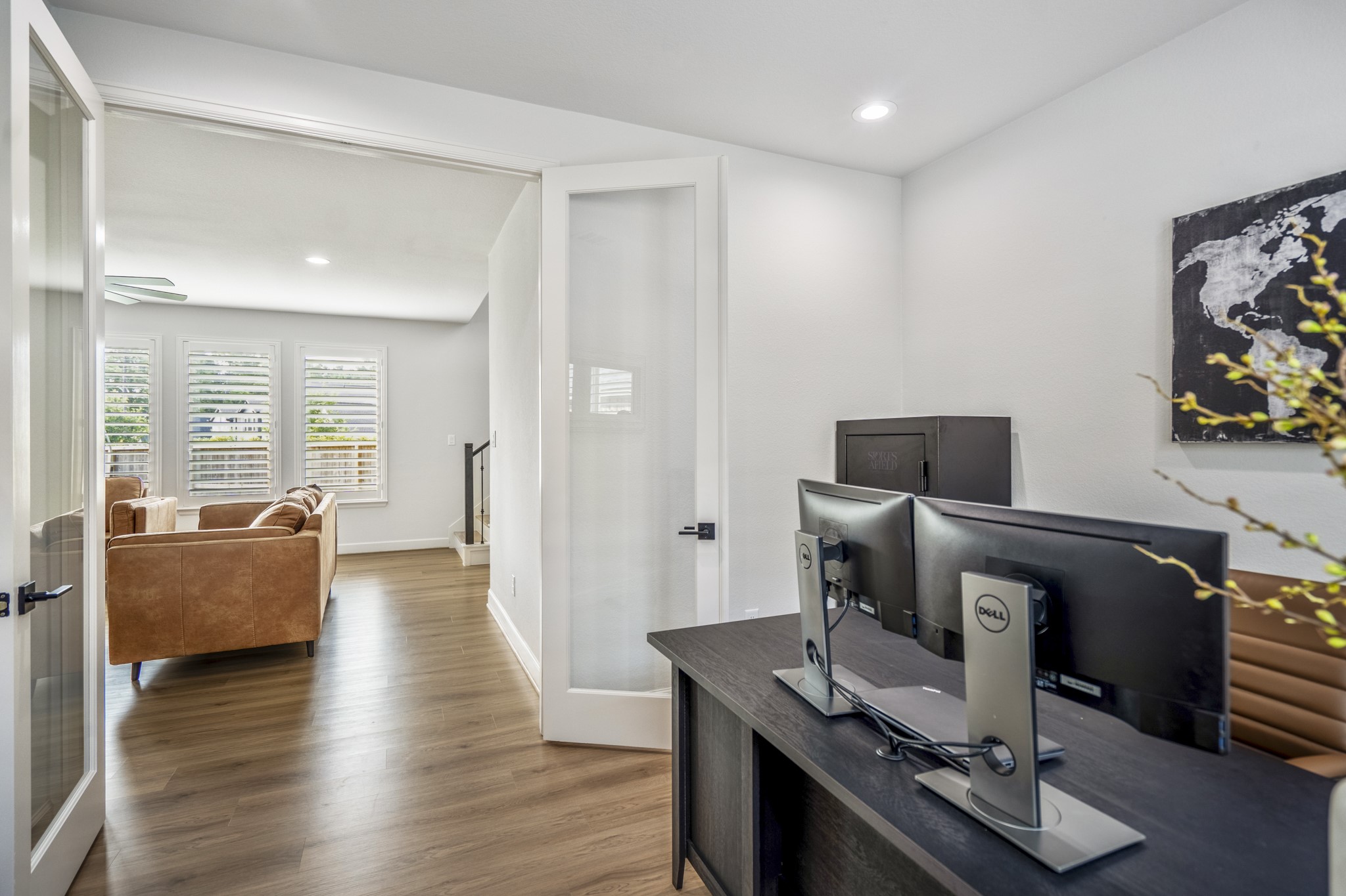 This modern home office with double glass doors and continuous LVP flooring sits just off the living room.