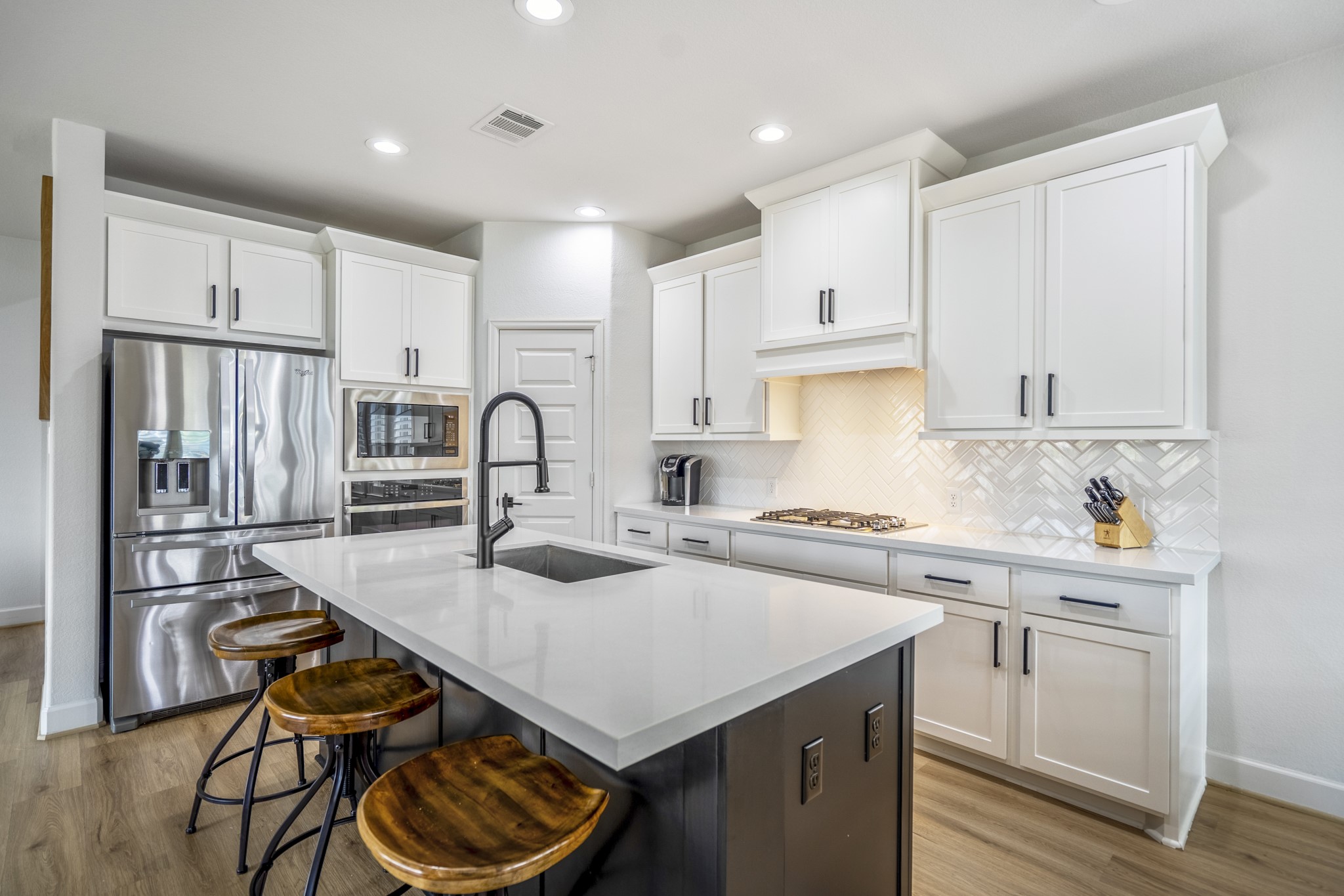The herringbone backsplash and recessed lighting add a touch of elegance to the space.