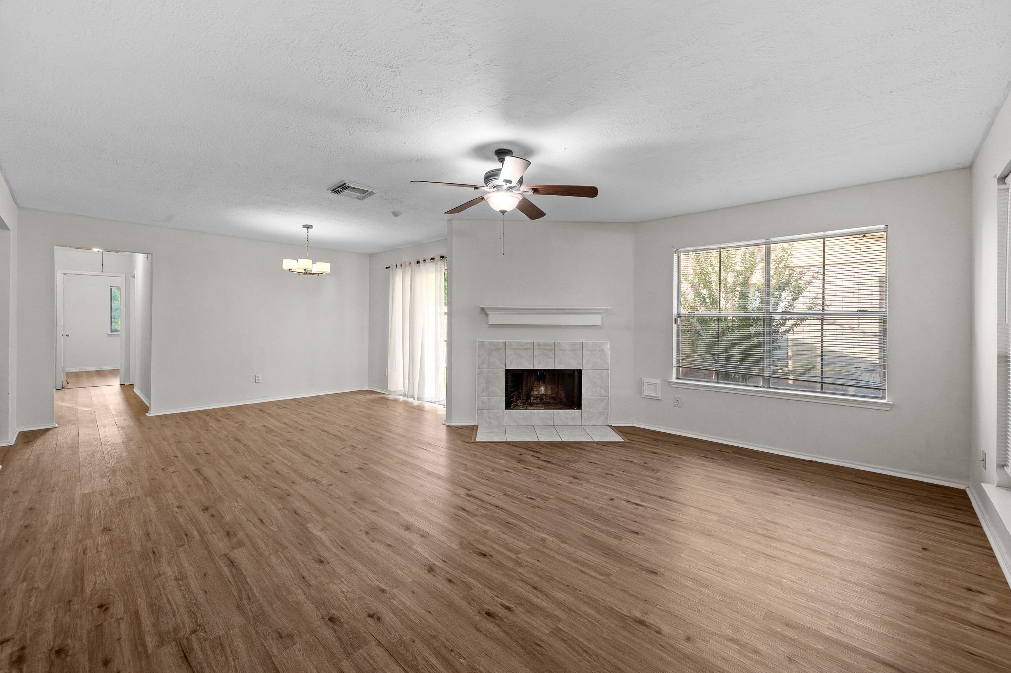 Spacious living area with beautiful flooring, a cozy fireplace, and ample natural light from large windows, creating an inviting atmosphere.