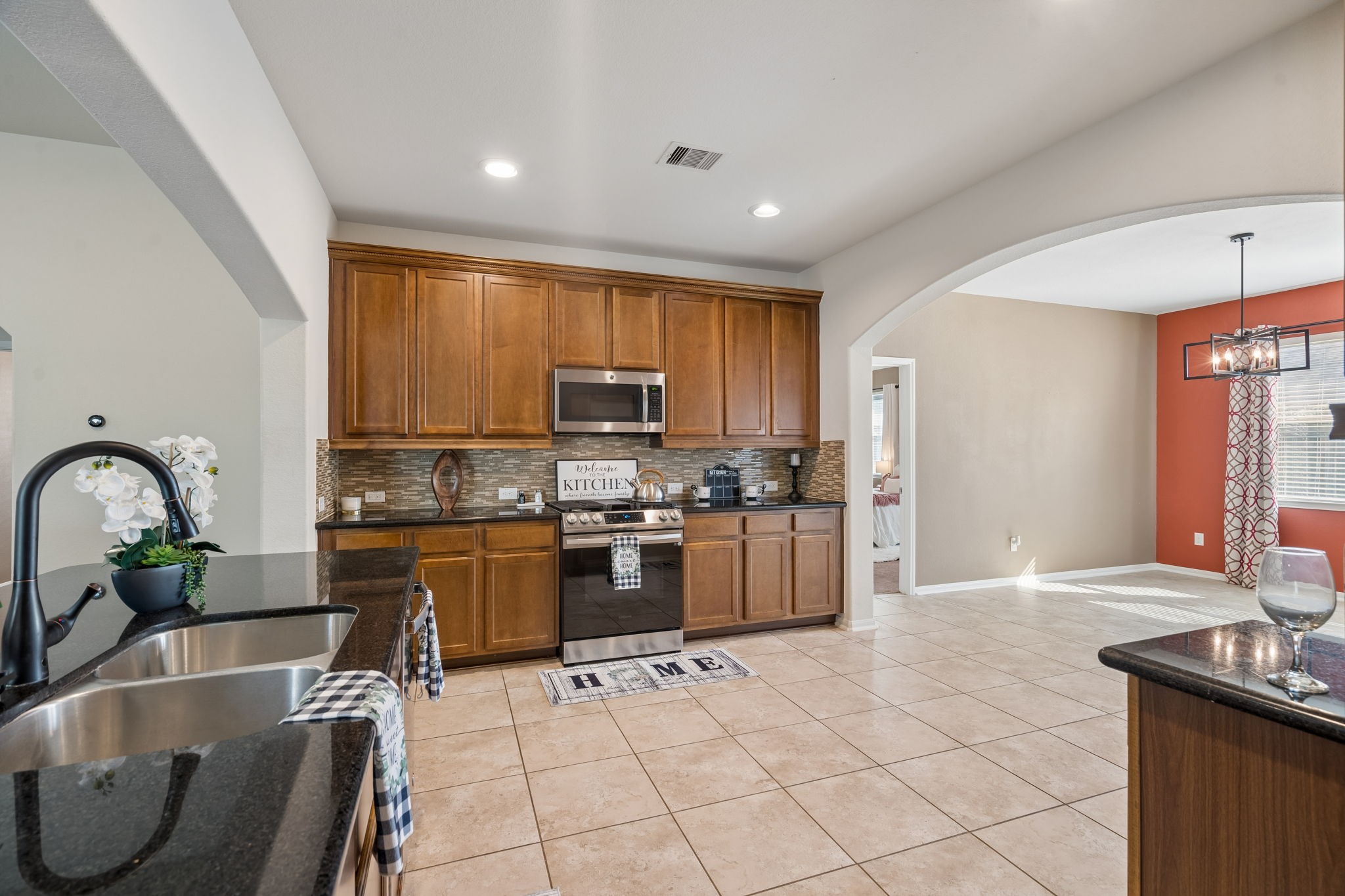 This generously sized kitchen offers abundant wood cabinetry, granite countertops, stainless steel appliances, a decorative tile backsplash and recessed lighting