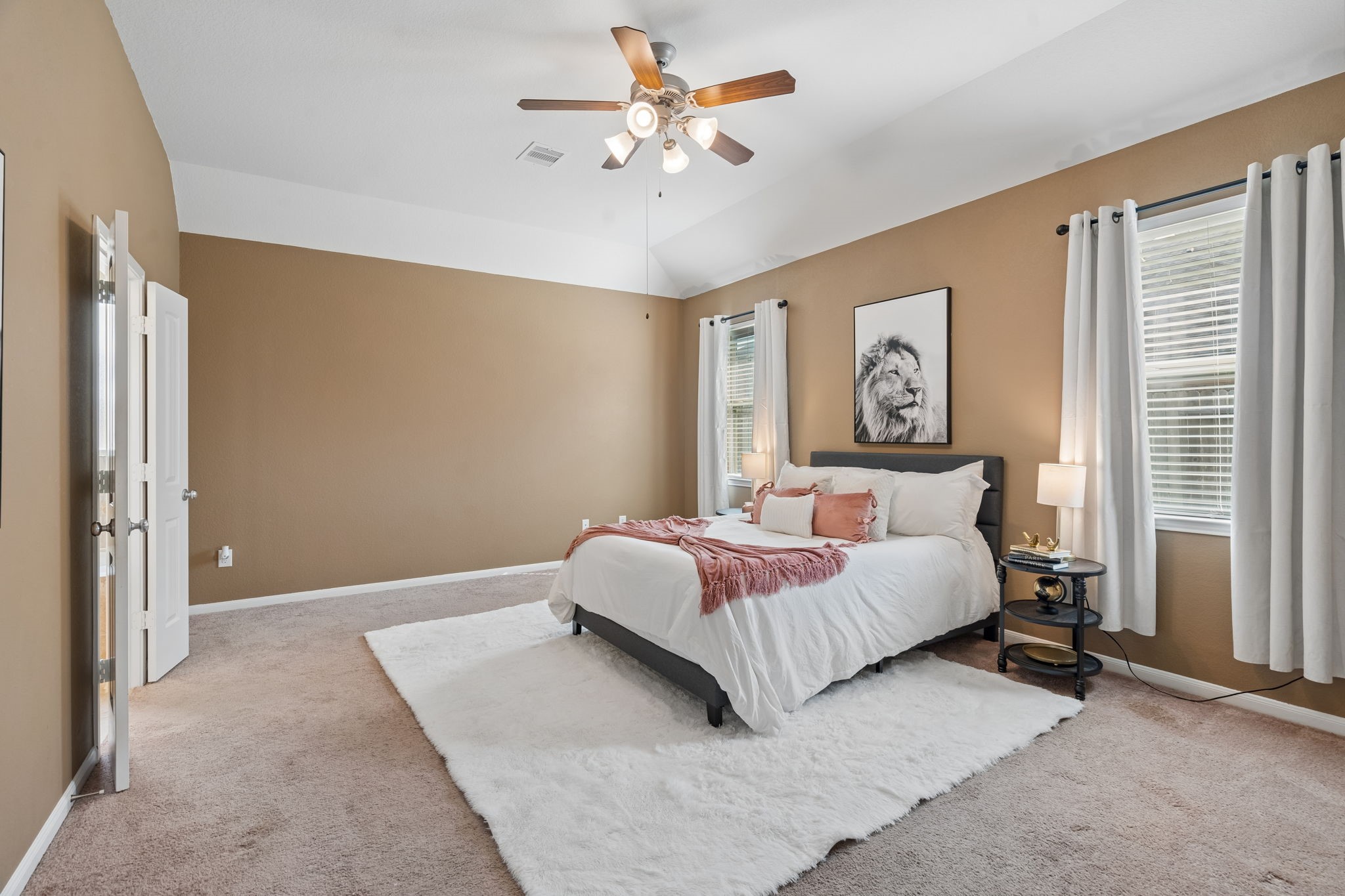 The generously sized primary bedroom features high ceilings, soft carpeting, a ceiling fan and two windows that welcome natural light. Plenty of room without sacrificing comfort or space.