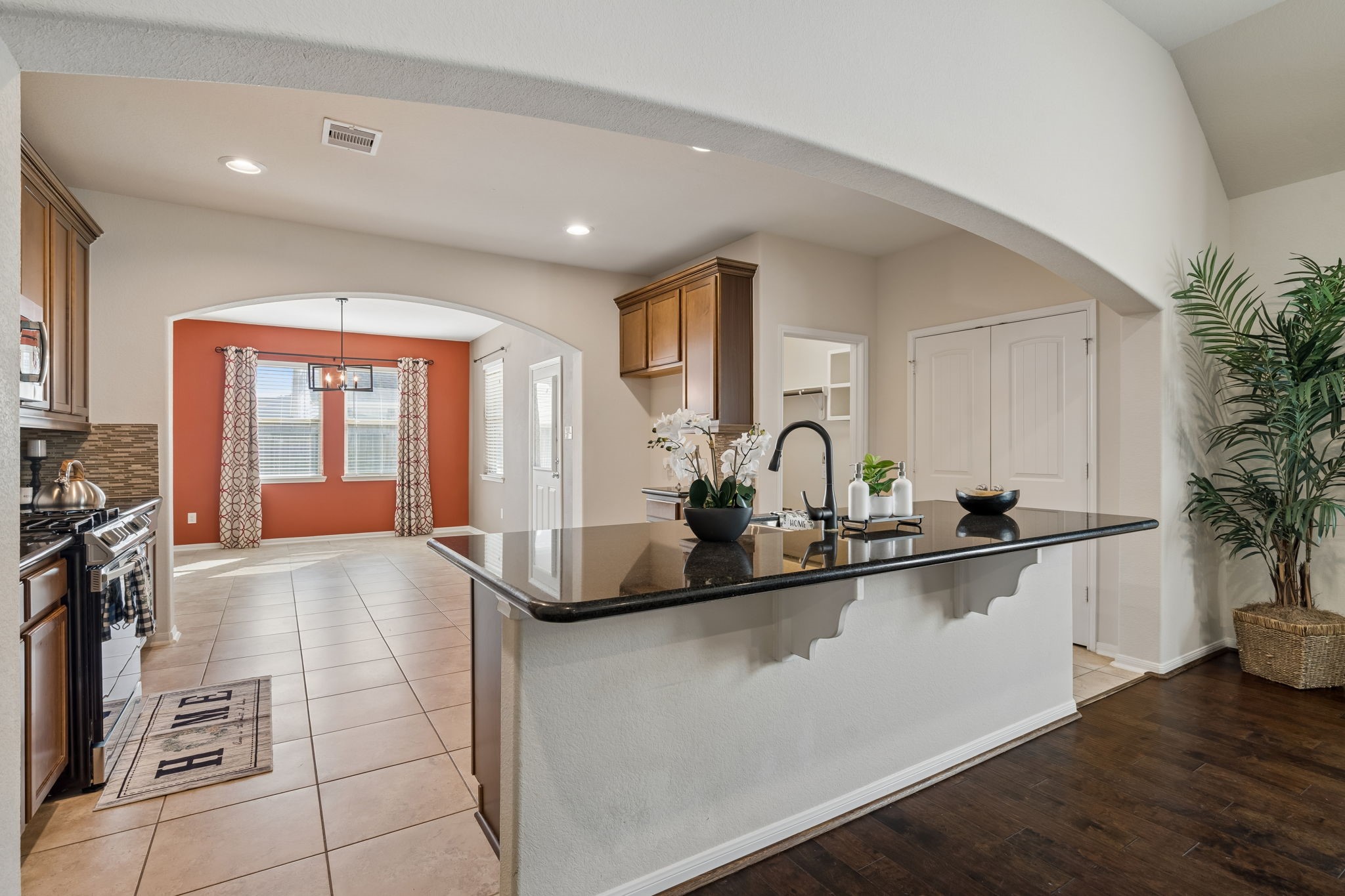 A generous granite breakfast bar overlooks the living room, while warm wood cabinetry, tile flooring, and an open connection to the breakfast area create an inviting space for cooking, conversation and everyday gatherings