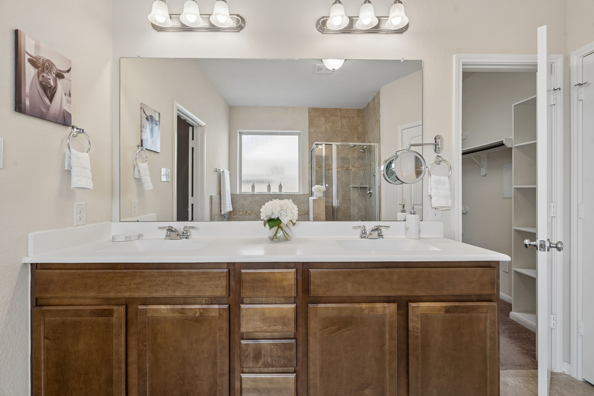Just beyond the vanity, a spacious walk-in closet with built-in shelving