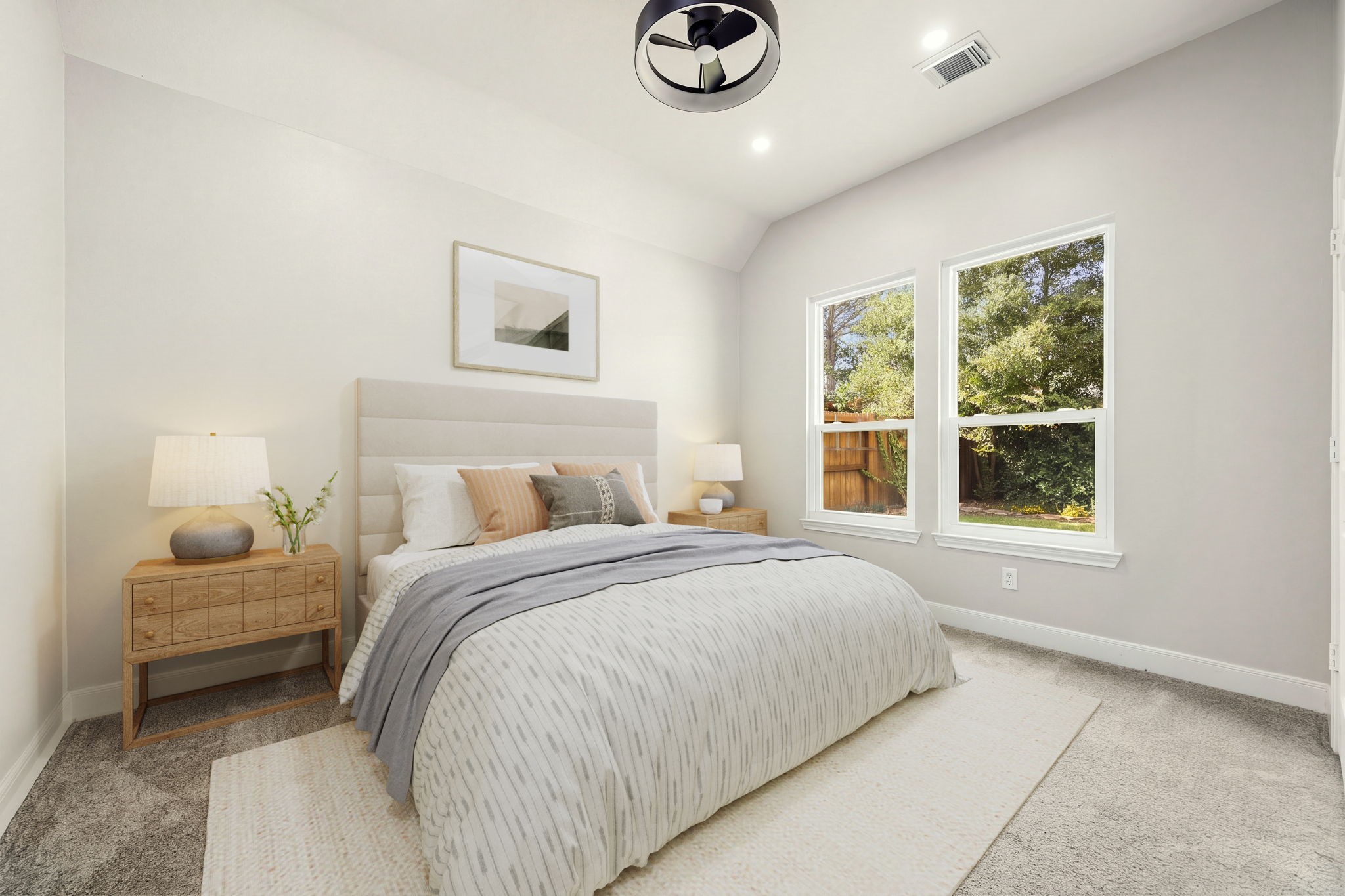 This welcoming secondary bedroom features neutral walls, plush carpeting, a modern ceiling fan, and high ceilings that create an open, airy feel. Large twin windows offer a serene view of the outdoor greenery while filling the space with beautiful natural lightmaking it ideal for family, guests, or a creative space.