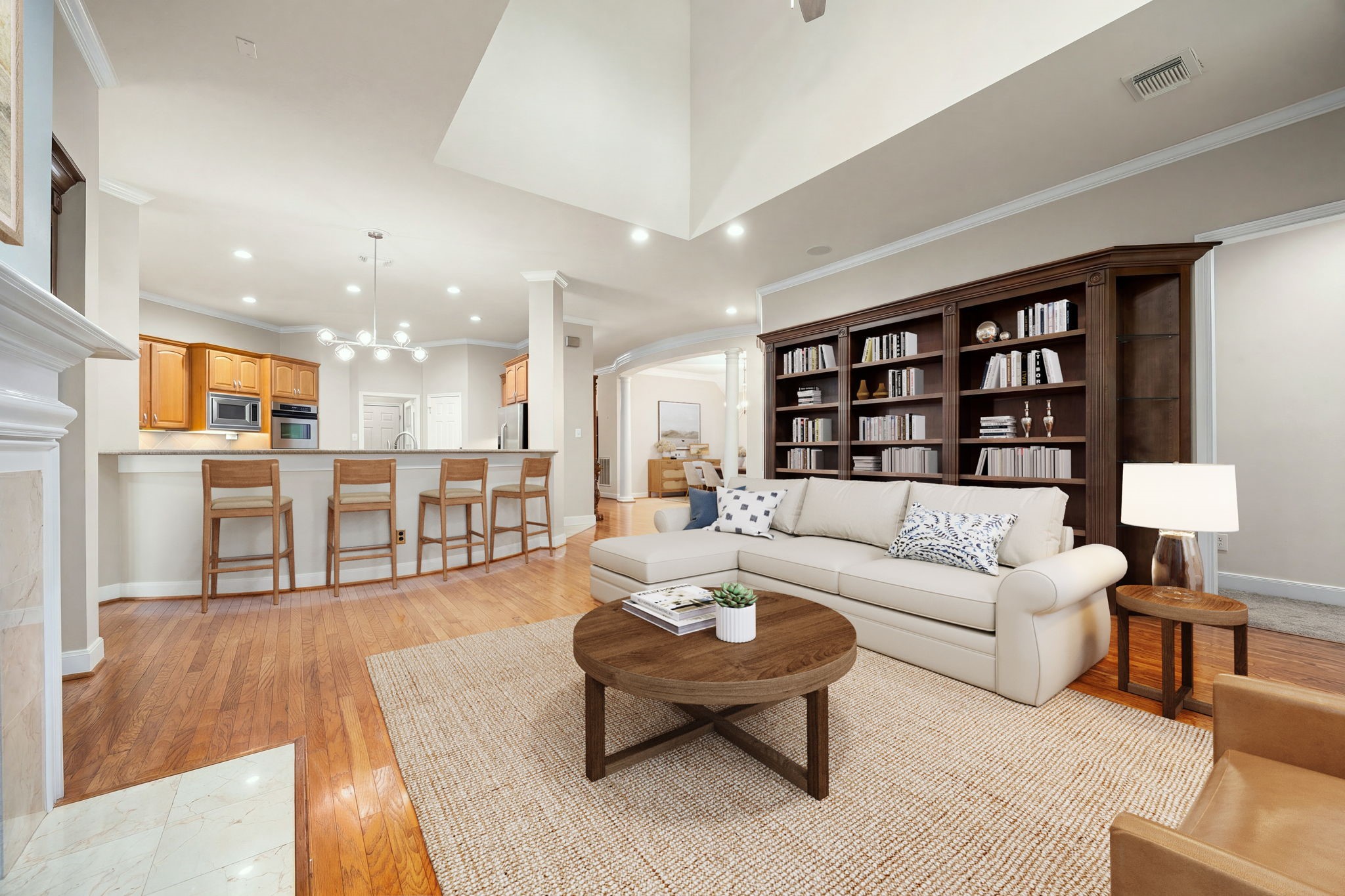 This perspective showcases how beautifully the expansive family room connects directly to the kitchen's raised breakfast bar. Perfect for casual dining and seamless entertaining, the layout keeps the chef connected to the conversation while highlighting the home's impressive flow and rich wood flooring. This perspective showcases how beautifully the expansive family room connects directly to the kitchen's raised breakfast bar. Perfect for casual dining and seamless entertaining, the layout keeps the chef connected to the conversation while highlighting the home's impressive flow and rich wood flooring.