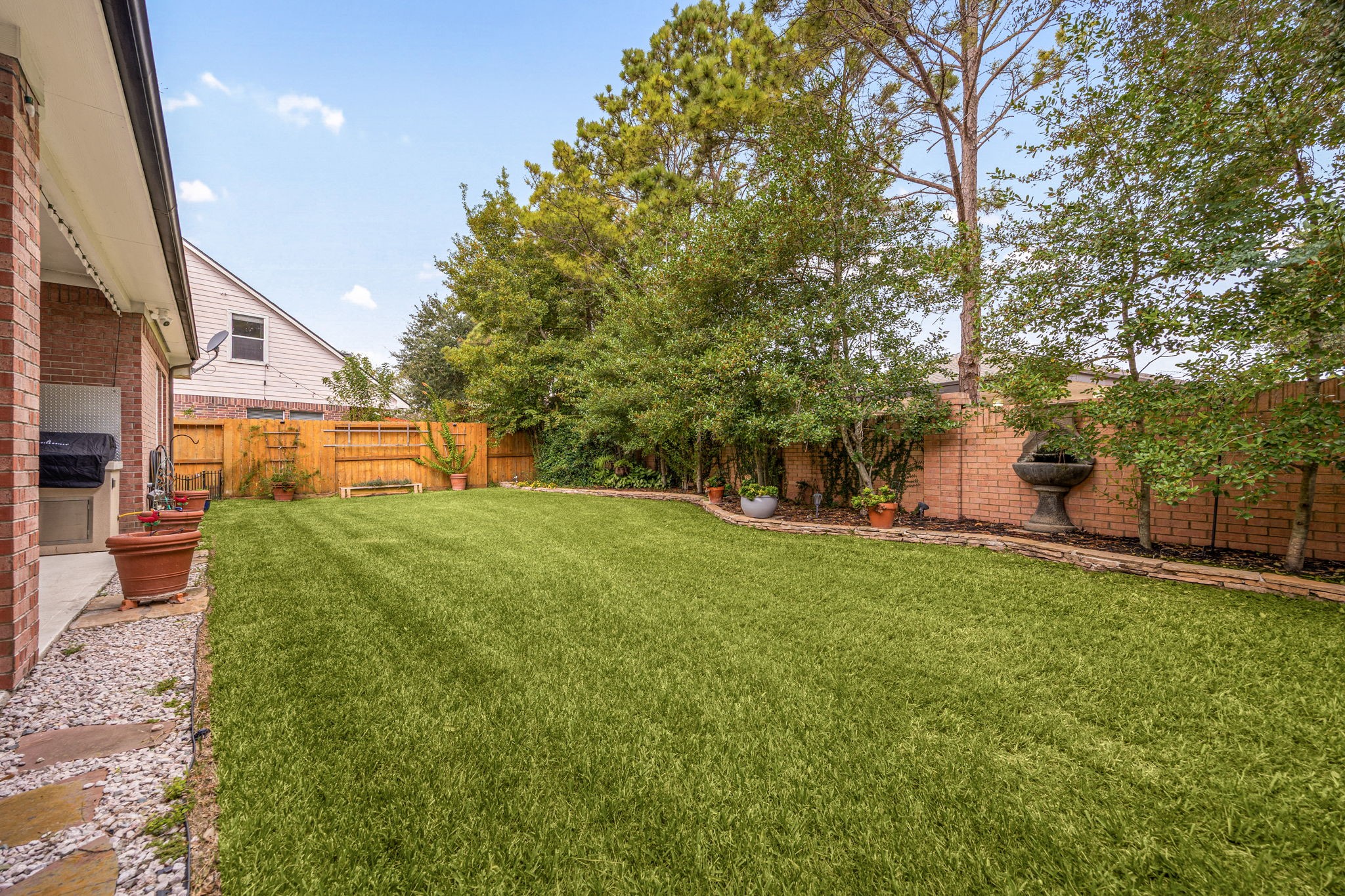 This wide daytime view highlights the immense scale of the lush green lawn, framed by a thick line of mature, towering privacy trees along the back fence line. Offering a pristine, sprawling space with no immediate rear windows looking down onto you, its the ultimate canvas for a future custom pool, playground, or serene outdoor retreat.