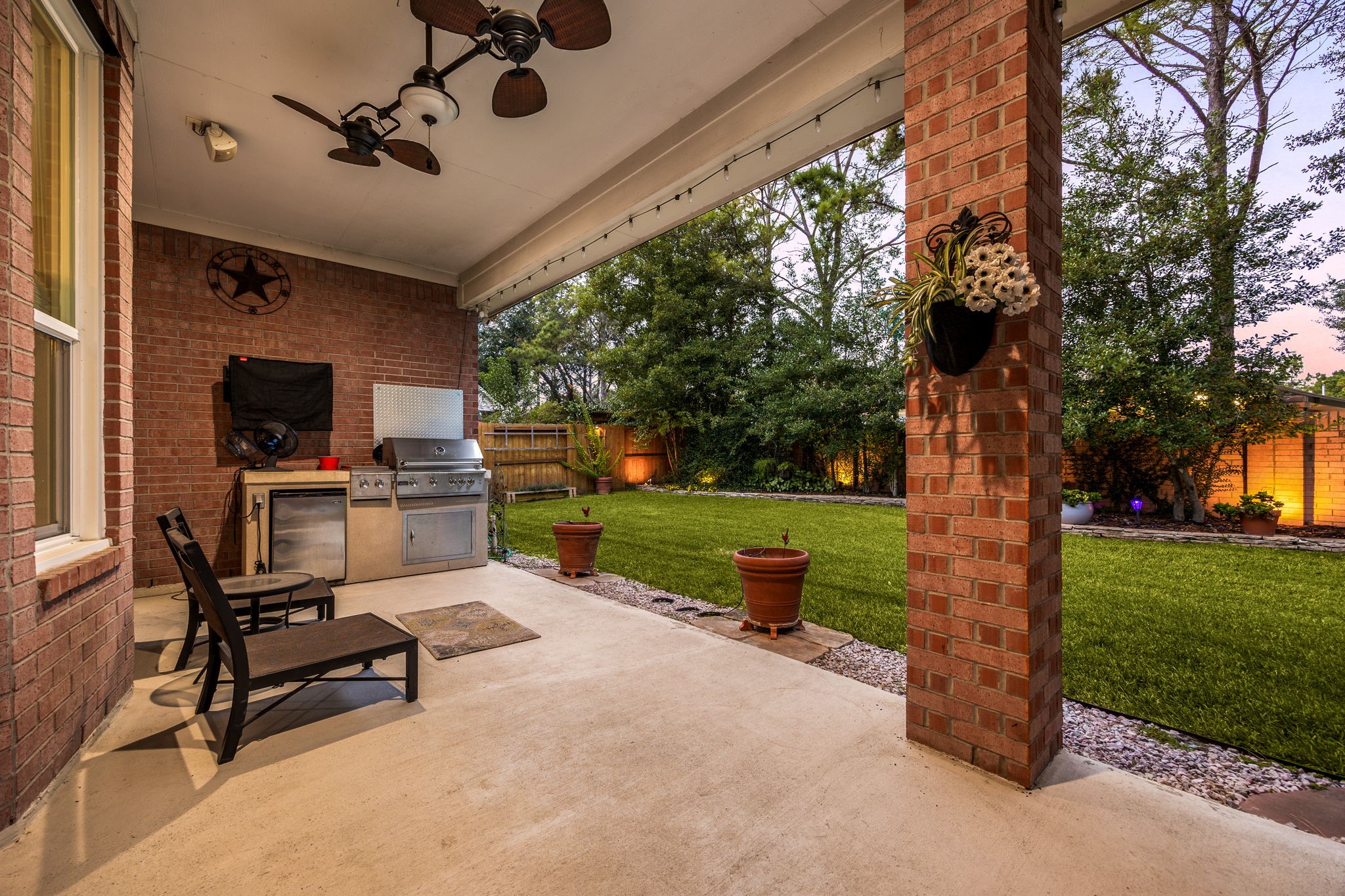 This reverse view of the covered patio highlights the beautifully manicured, tree-lined backyard that provides exceptional privacy. The expansive green lawn offers plenty of space for pets to run, kids to play, or even a future swimming pool, perfectly completing this remarkable Cinco Ranch home.