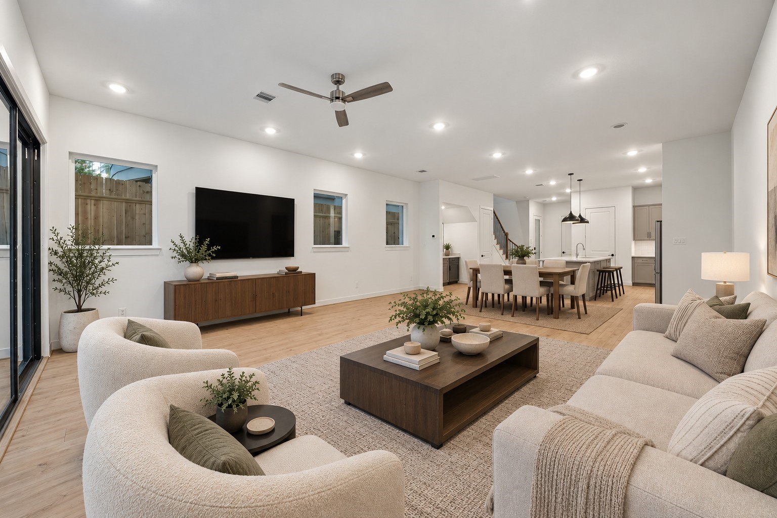 Digitally staged spacious living area featuring a comfortable seating arrangement, modern finishes, and an open layout that flows seamlessly into the dining area and kitchen.