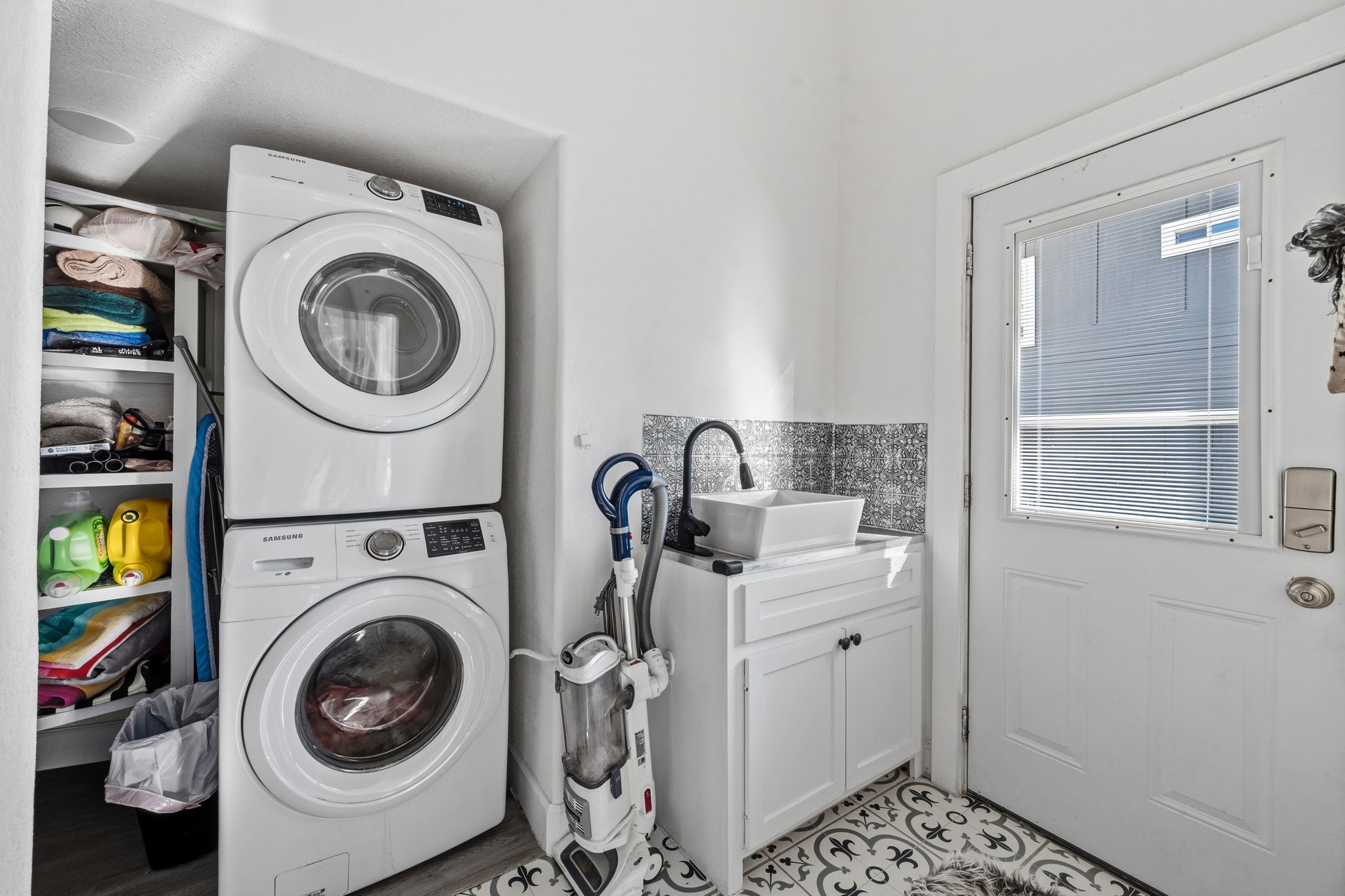 A dedicated laundry room with stacked machines and shelving.