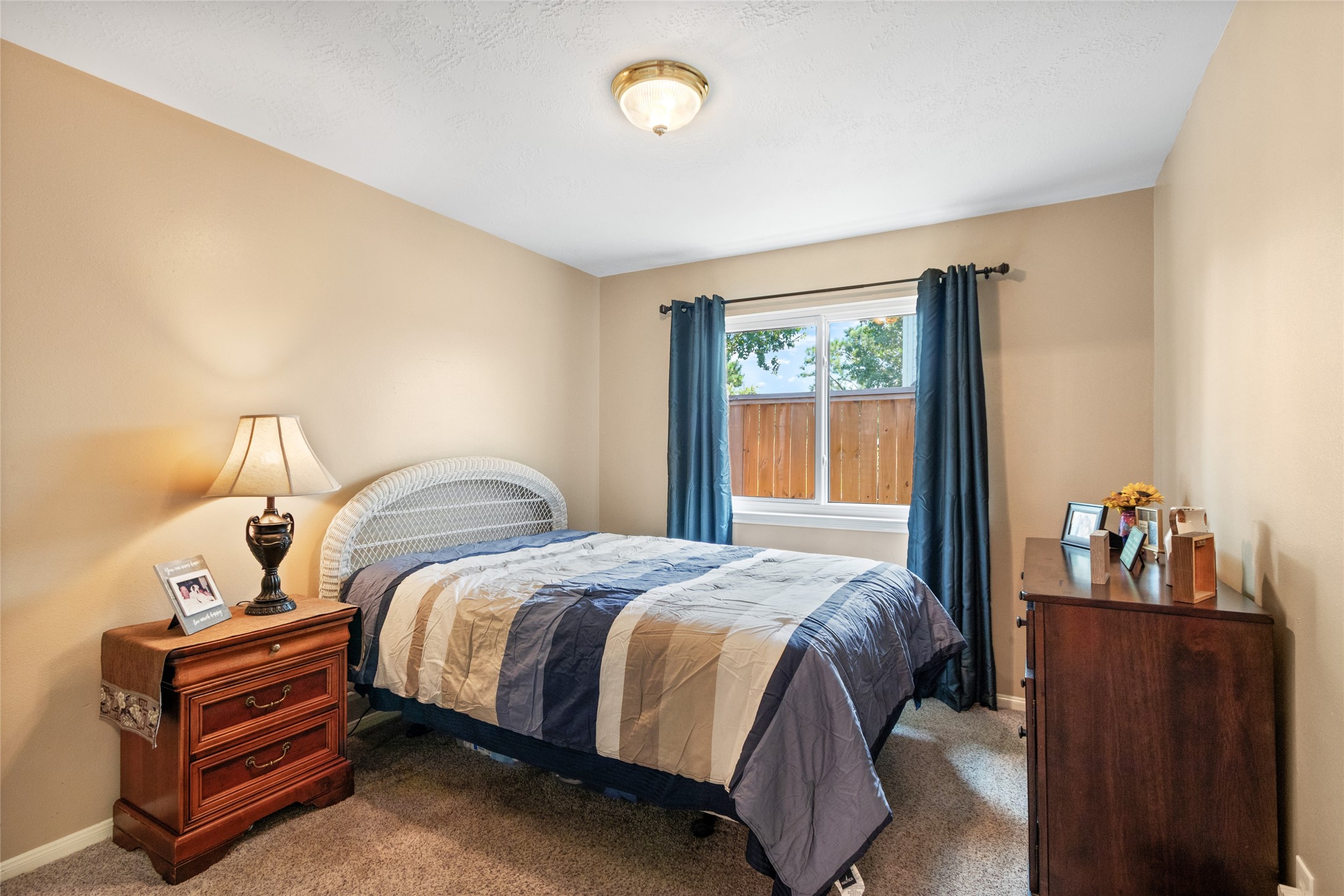 Cozy bedroom with neutral walls, a large window for natural light, and space for a double bed, nightstand, and dresser.