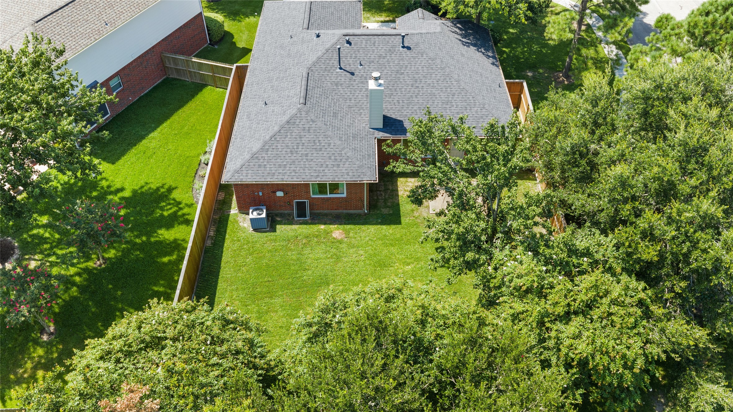 Charming brick home with a spacious, lush backyard and mature trees, perfect for outdoor activities and relaxation.