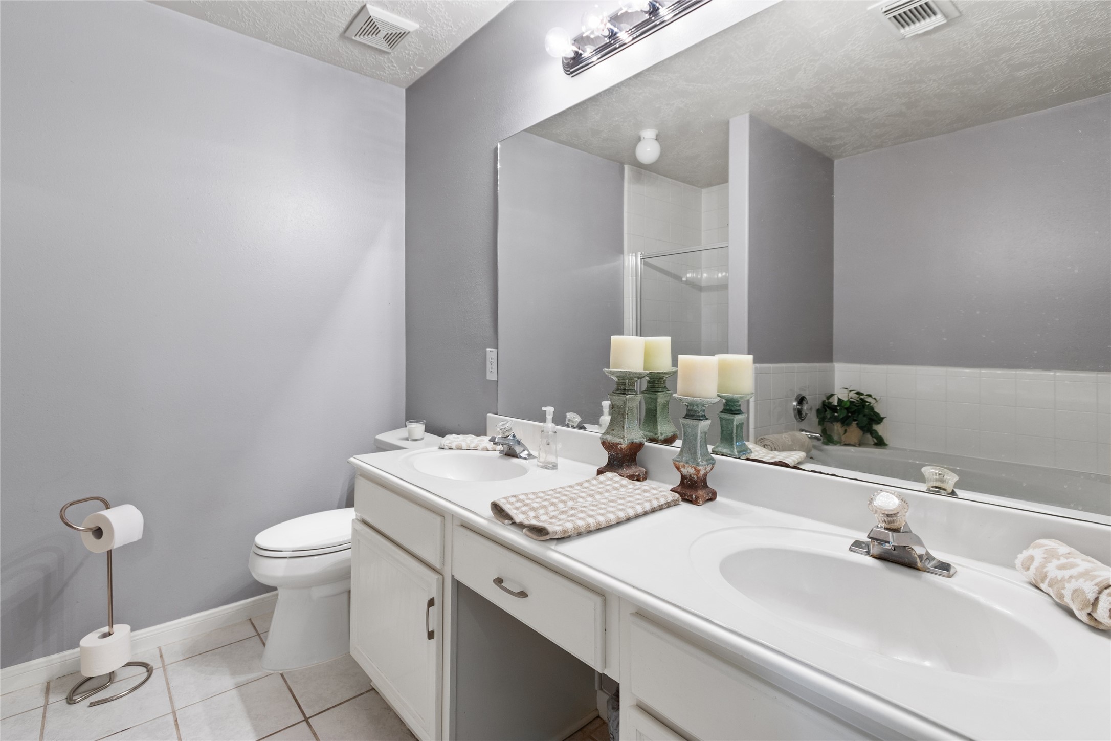 Elegant bathroom with dual sinks, modern fixtures, and ample counter space, complemented by soft gray walls and bright lighting for a serene atmosphere.
