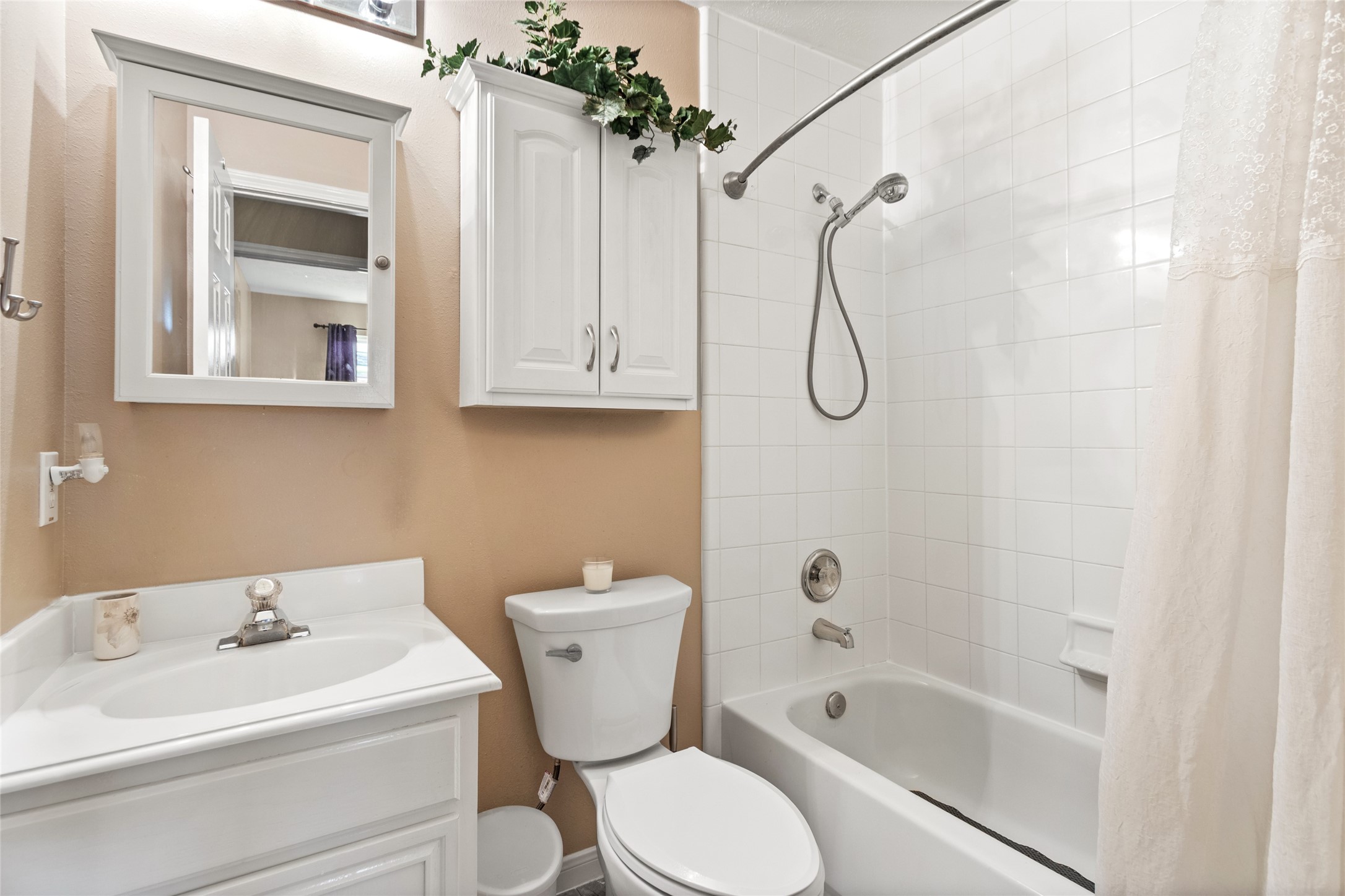 Charming bathroom featuring a classic white tub with a handheld shower, complemented by a sleek vanity, mirrored cabinet, and ample storage.