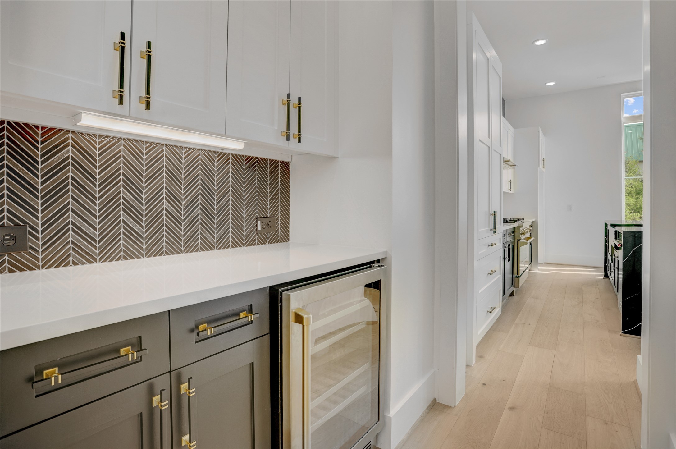 The butler's pantry divides the kitchen and dining and features a dry bar area with a wine fridge and additional storage space. Virtually staged photo. The butler's pantry divides the kitchen and dining and features a dry bar area with a wine fridge and additional storage space. Virtually staged photo.