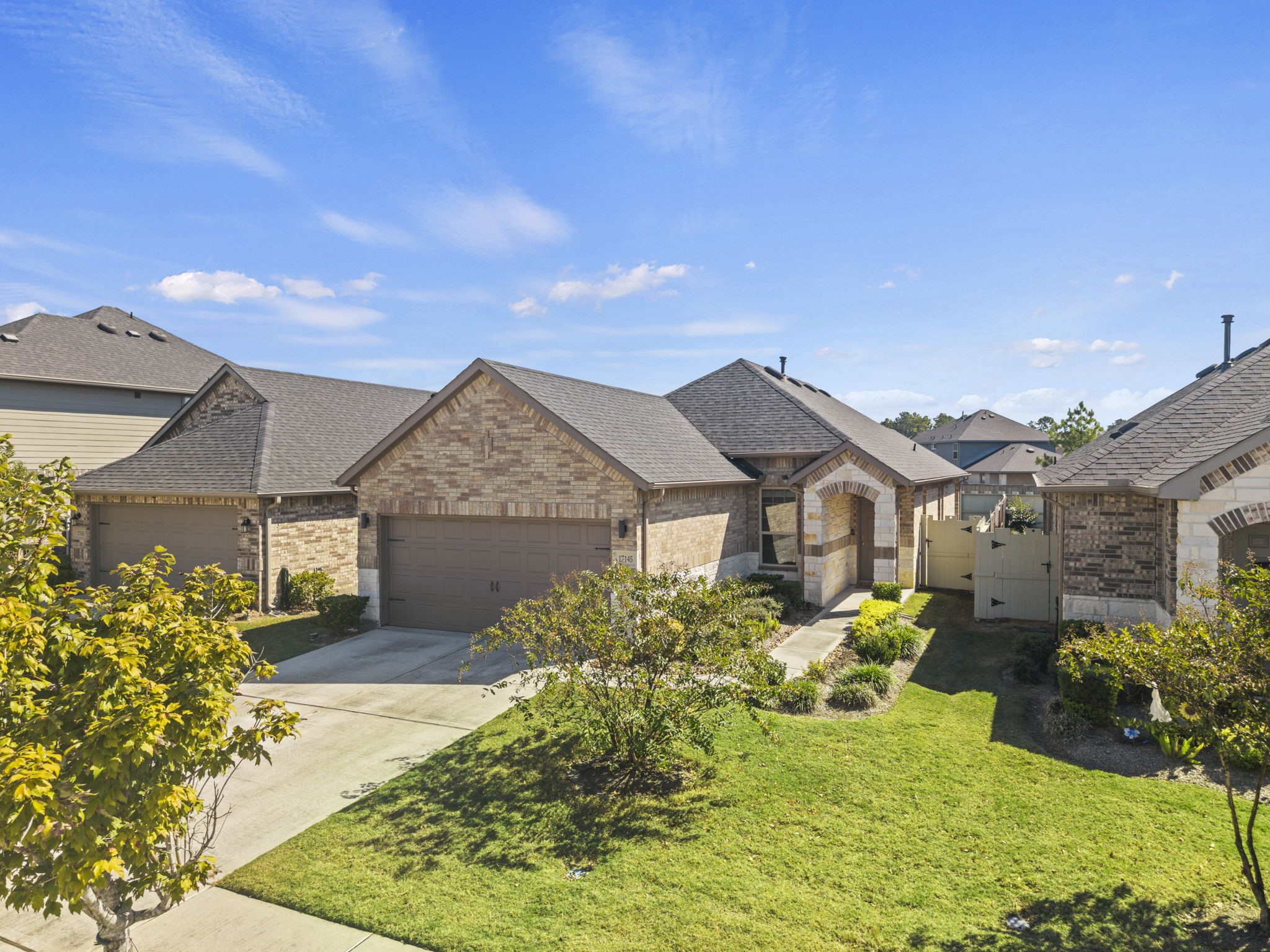 Charming single-story brick home featuring a welcoming covered entry, a two-car garage, and a landscaped front yard with a spacious driveway.