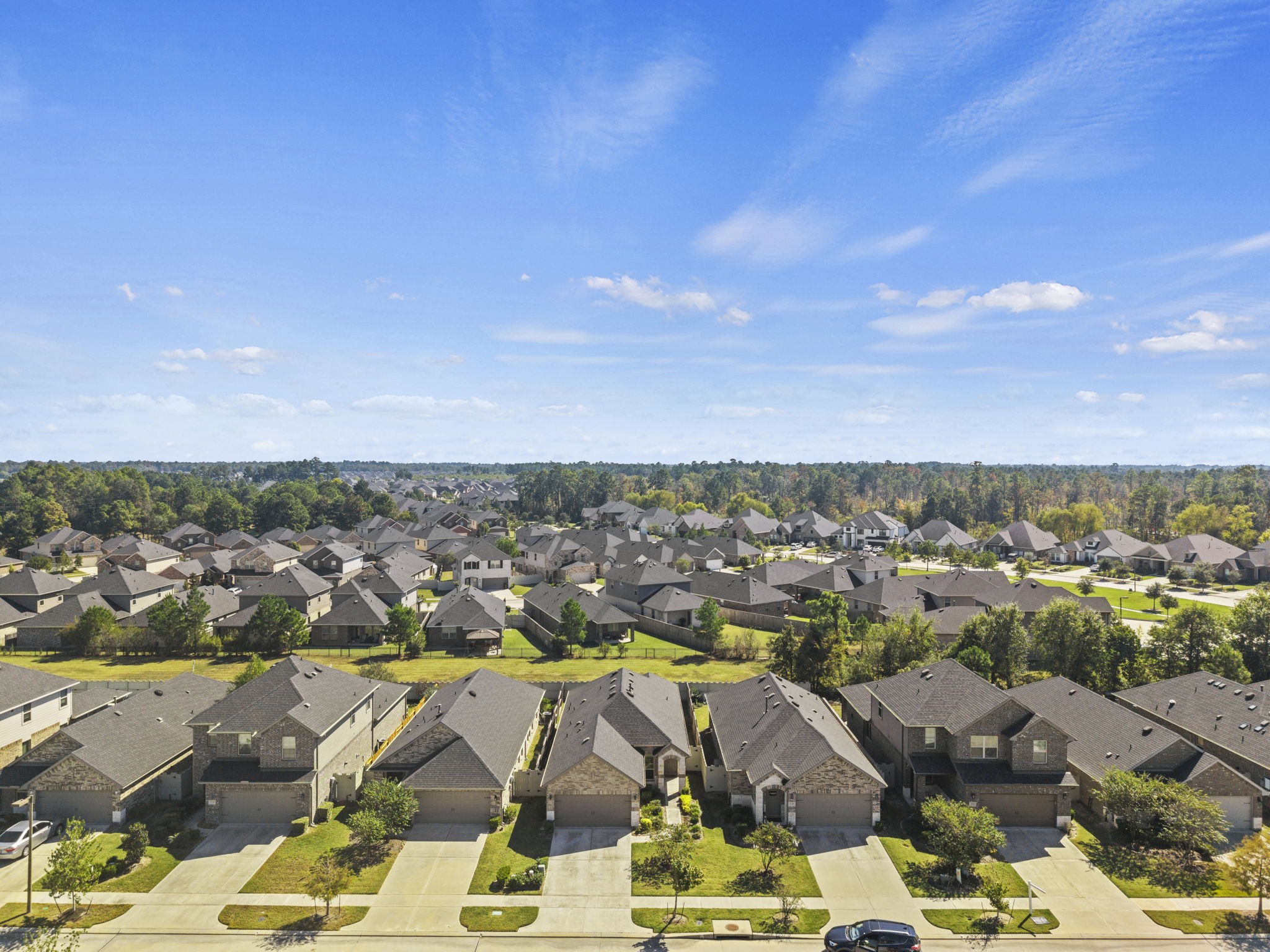 A birds-eye view showcasing the home's charming curb appeal, spacious driveway, and surrounding neighborhood.