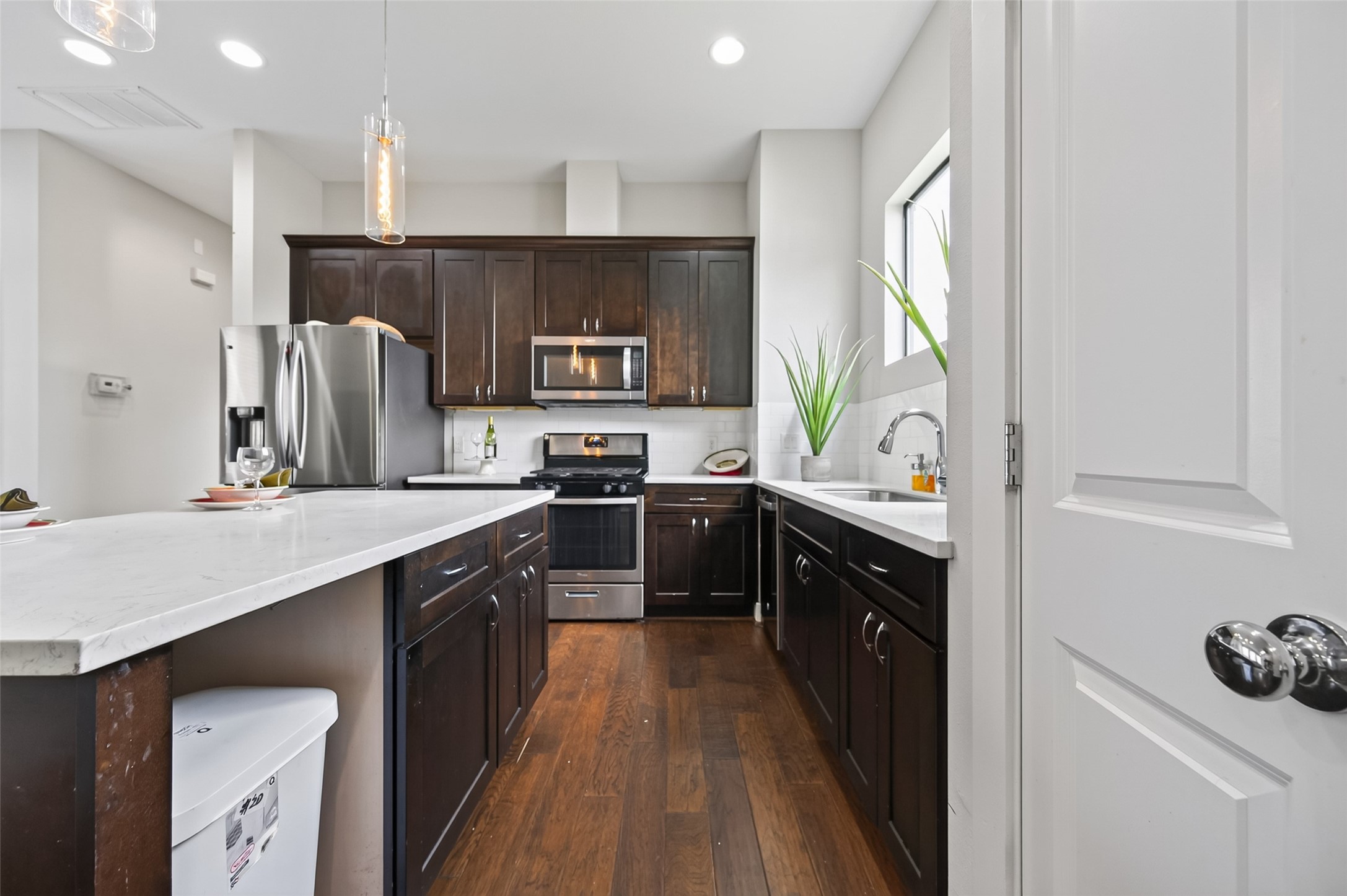 Bright and inviting space with elegant hardwood flooring and a high ceiling, featuring a versatile nook perfect for decor or storage.