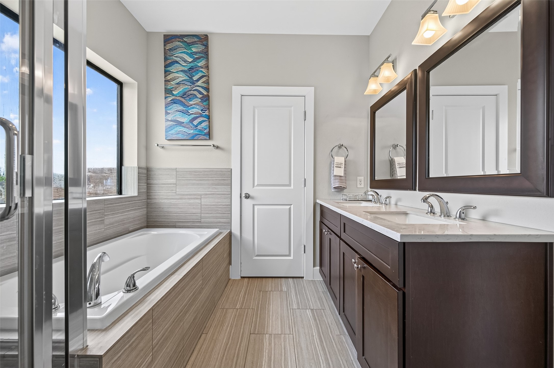 Elegant double vanity bathroom with marble countertops, rich wood cabinetry, and large framed mirrors, offering a blend of style and functionality.