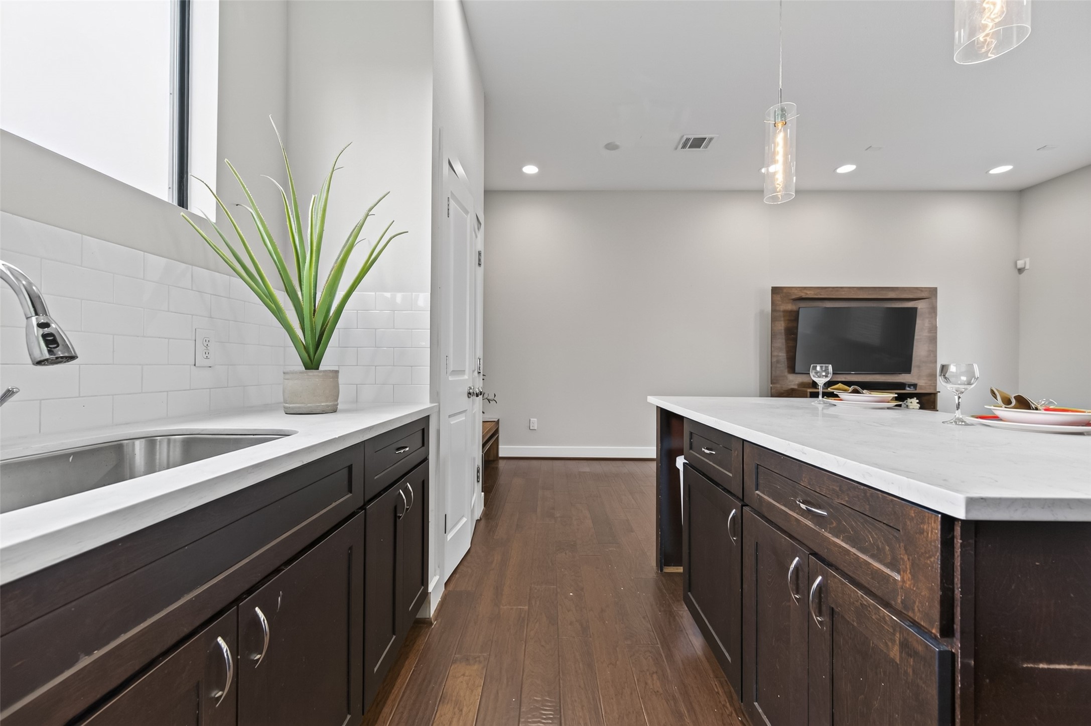 Modern kitchen with stainless steel appliances, dark wood cabinetry, and sleek white countertops.