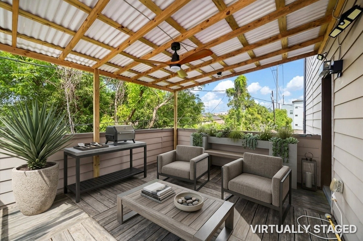 Charming covered deck with a stylish wooden ceiling and fan, perfect for enjoying outdoor relaxation amidst lush greenery.