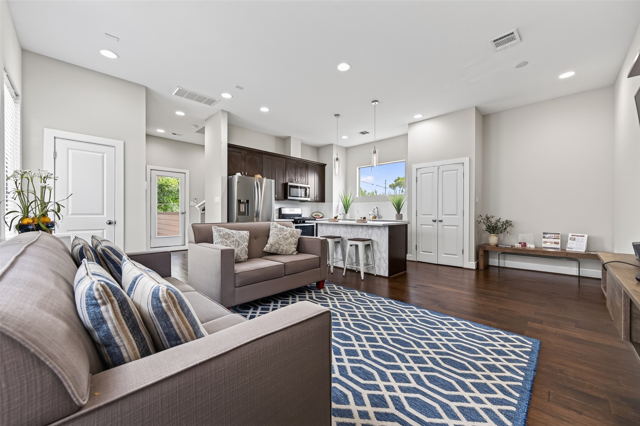 Bright and modern living space with an open-concept design, featuring sleek hardwood floors, a stylish kitchen with a marble countertop island, and a cozy seating area perfect for relaxation.