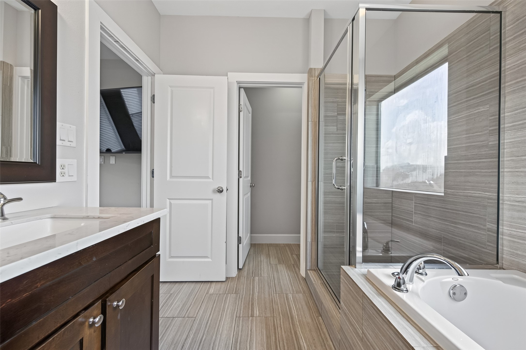 Elegant bathroom featuring a sleek glass-enclosed shower, modern fixtures, and a luxurious bathtub with a large window offering plenty of natural light.