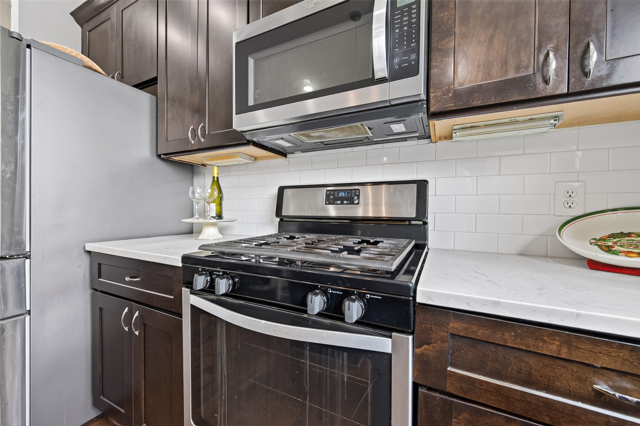 Modern kitchen with sleek stainless steel appliances, dark wood cabinetry, and a spacious island, seamlessly flowing into a cozy living area with ample natural light.