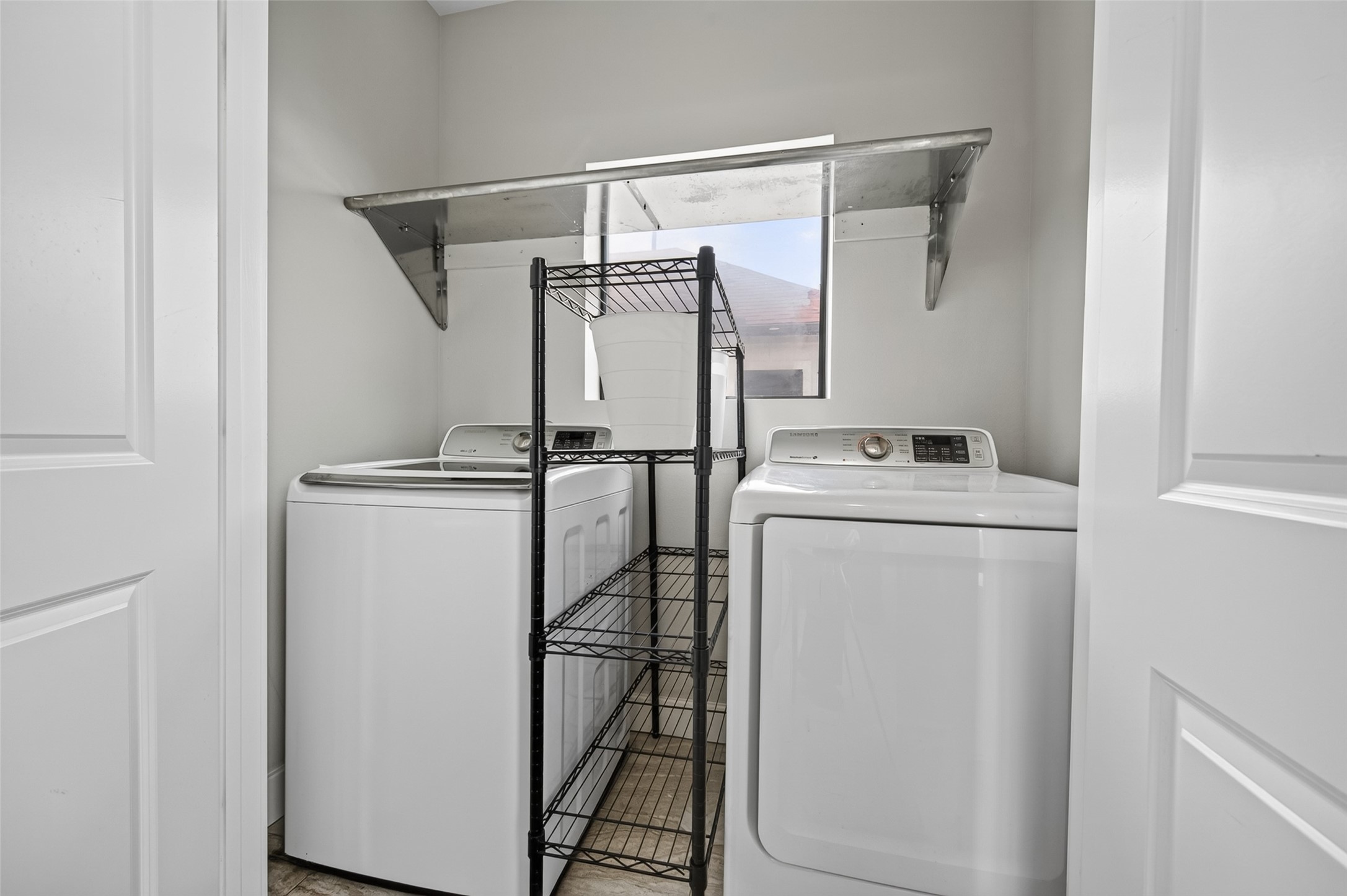 Convenient laundry room with modern washer and dryer, featuring ample shelving for storage and organization.