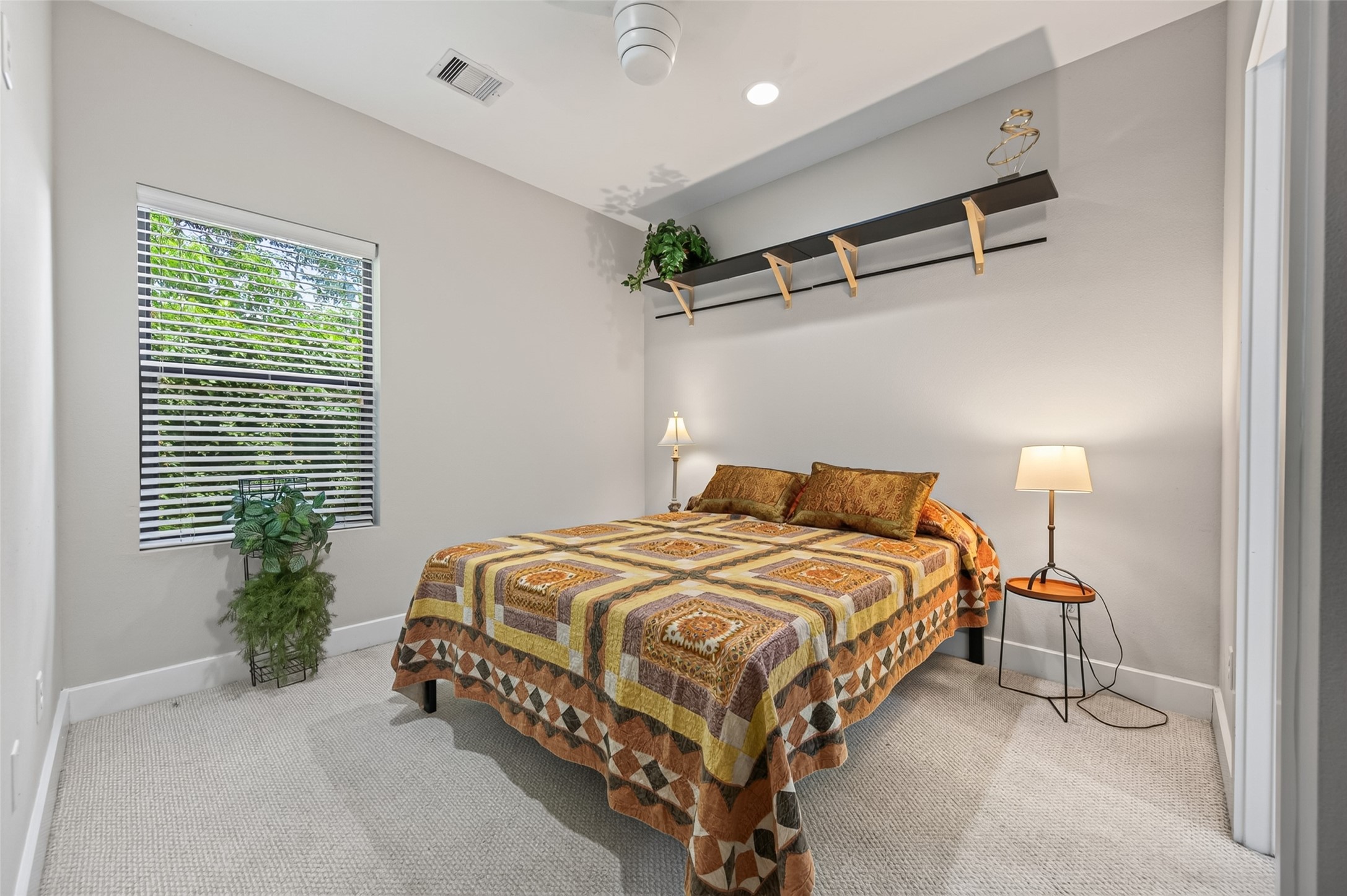 Cozy bedroom with a warm quilted bedspread, soft lighting, and en-suite bathroom access.