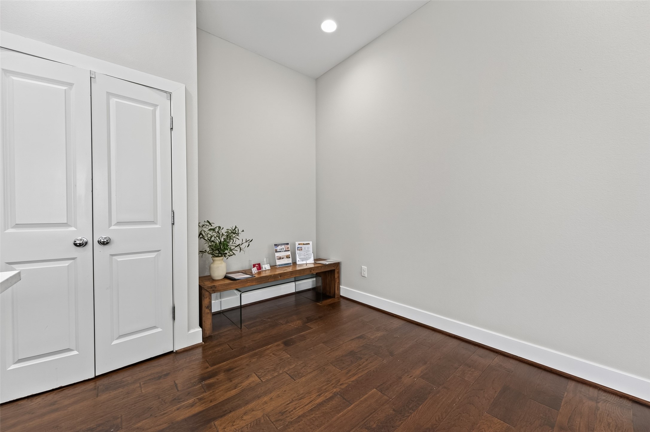 Bright and inviting living room featuring sleek hardwood floors, modern recessed lighting, and a stylish wall-mounted entertainment center. Large windows with blinds provide ample natural light, enhancing the open and airy feel.