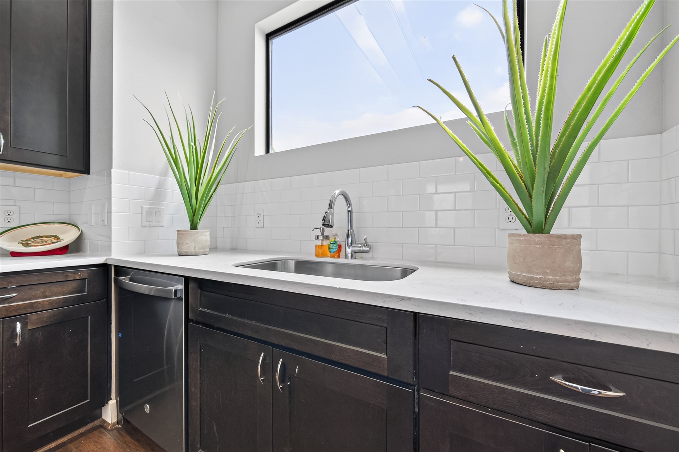 Sleek kitchen featuring rich dark wood cabinetry, stainless steel appliances, and elegant marble countertops, offering ample workspace and a modern aesthetic.
