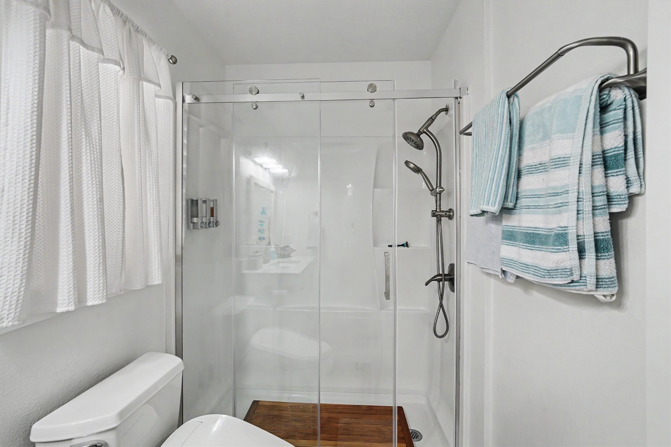 A spacious walk-in shower with a sleek seamless glass door creates a clean, modern retreat.