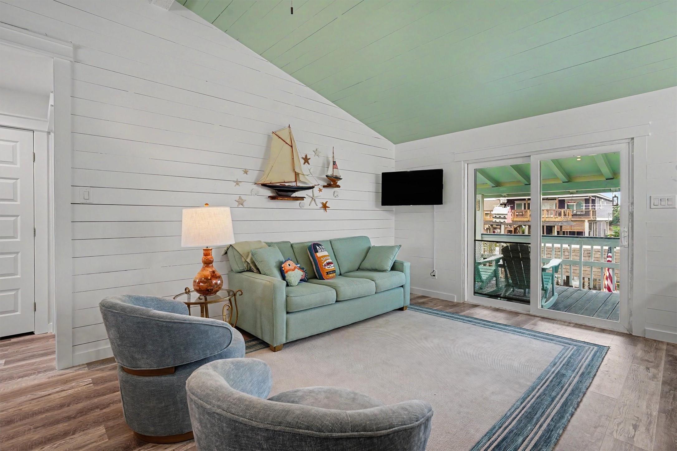 Modern doors, stylish lighting, beautiful flooring, and waterfront views come together to create a living space that feels fresh, coastal, and inviting