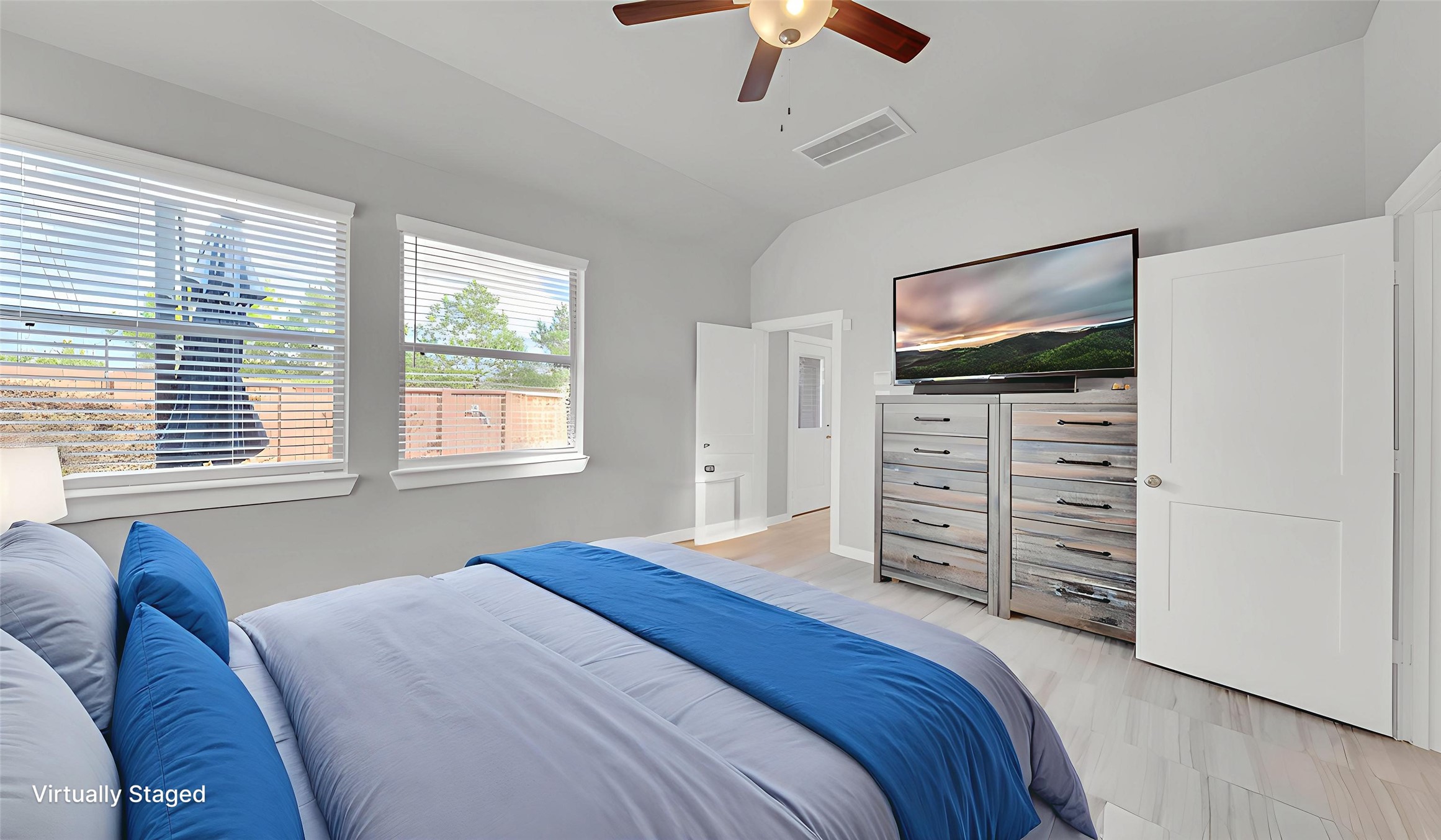 Spacious primary bedroom with large windows offering abundant natural light and backyard views.
