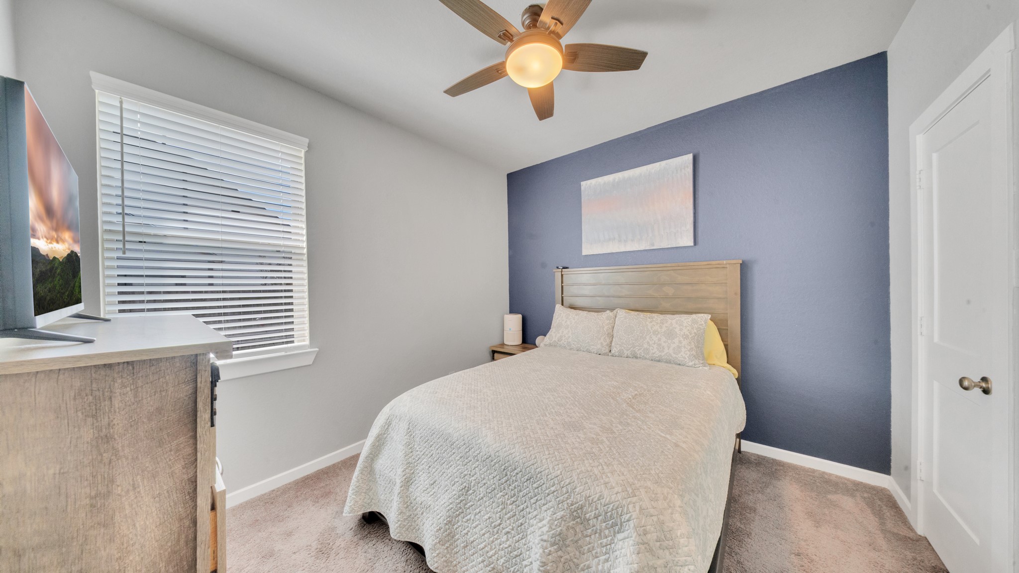 Comfortable secondary bedroom with natural light and a stylish accent wall.
