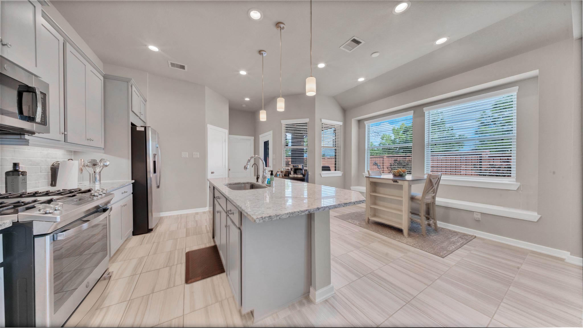 Modern stainless-steel appliances, gas range, and granite island ideal for cooking and entertaining.