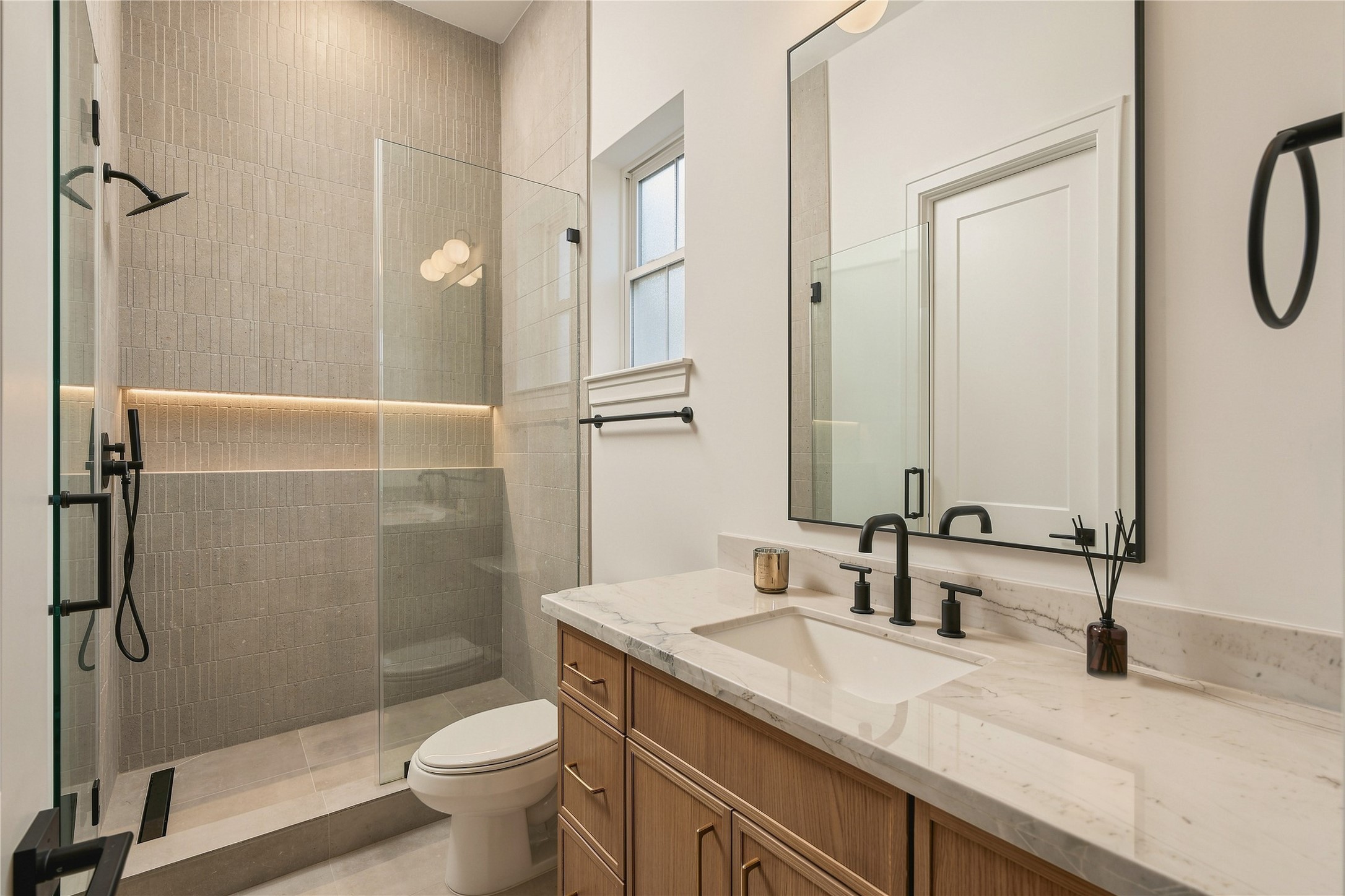 The study is complemented by its own full bath, finished with Mount Blanc Quartzite, designer tile extending to the ceiling, and a frameless glass showerallowing the space to easily function as a private
