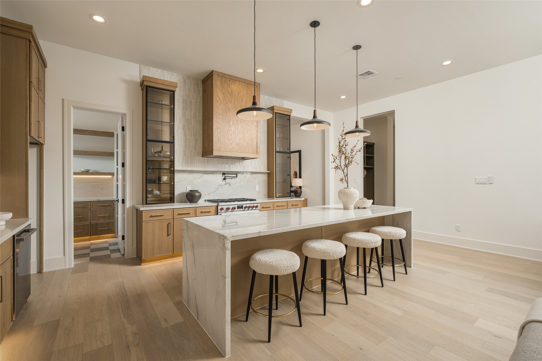 The kitchens generous scale and extended island seating create a true entertaining centerpiece, while the open layout maintains an effortless connection to the surrounding living spaces.