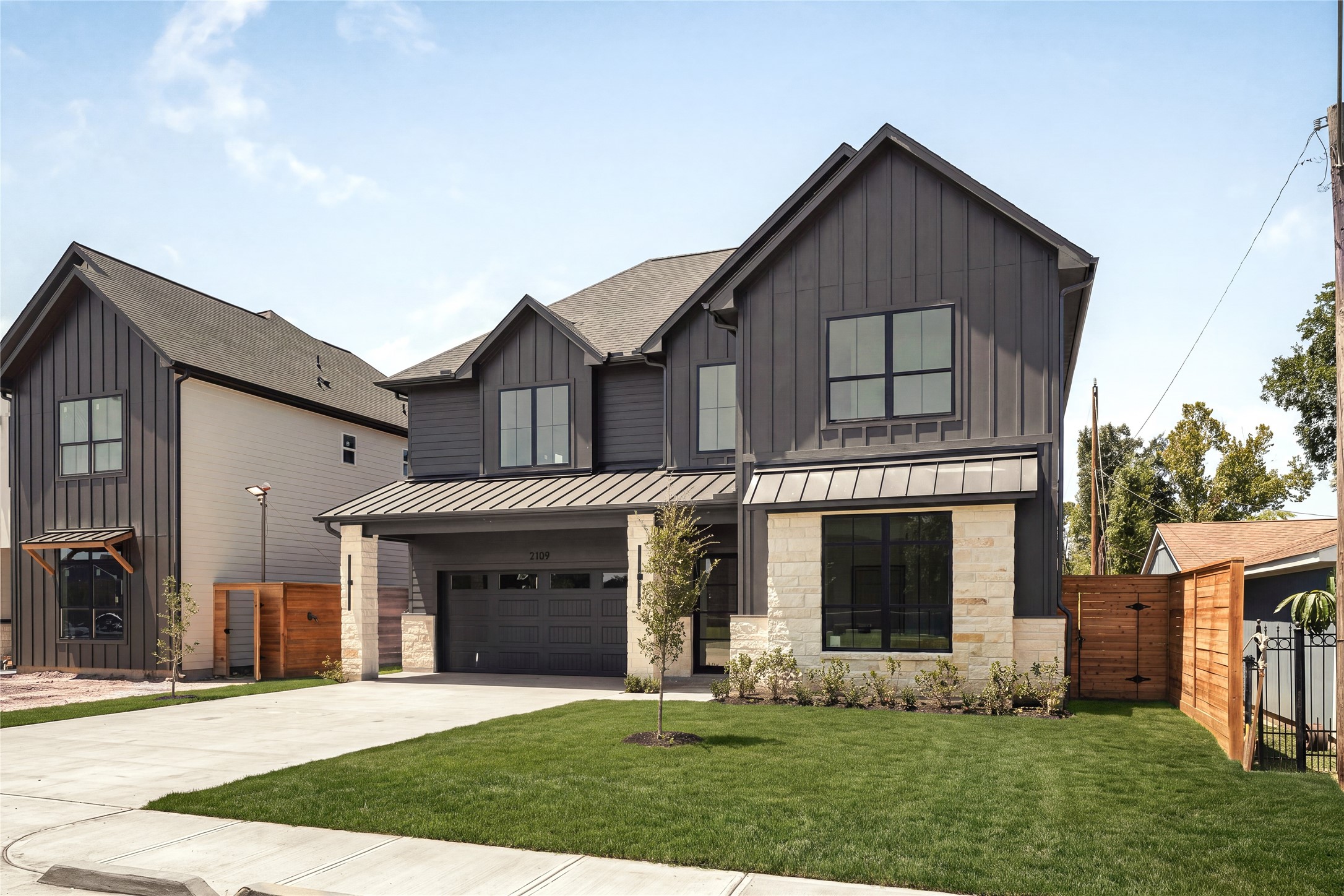A wider view captures the homes distinctive modern profile and layered rooflines, with a broad driveway and landscaped front lawn creating an impressive sense of arrival.