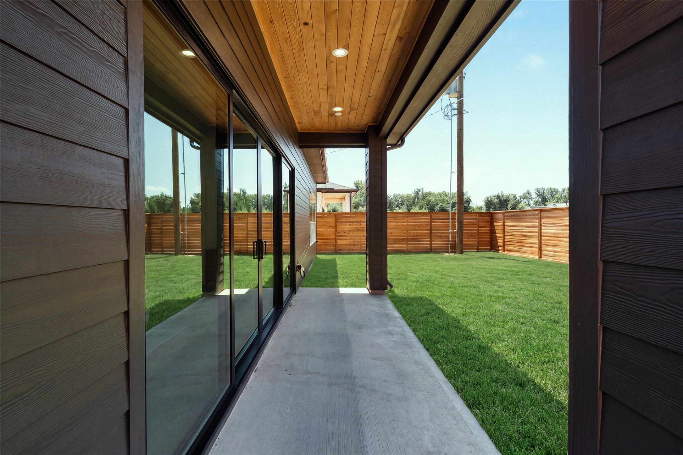 The covered patio creates a true outdoor extension of the home, framed by warm tongue-and-groove wood soffits and opening to an expansive 30' x 60' backyard with room to create a future pool or outdoor retreat.